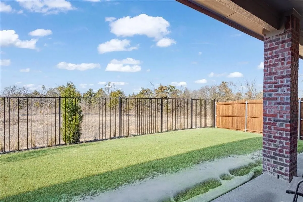 Covered patio with a brick column, concrete flooring, and an artificial turf lawn