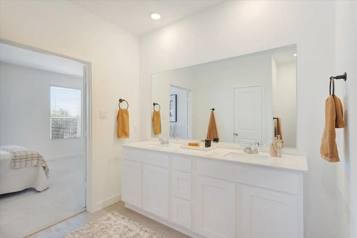 Double vanity with dual sinks, a stone countertop, and a large wall-mounted mirror