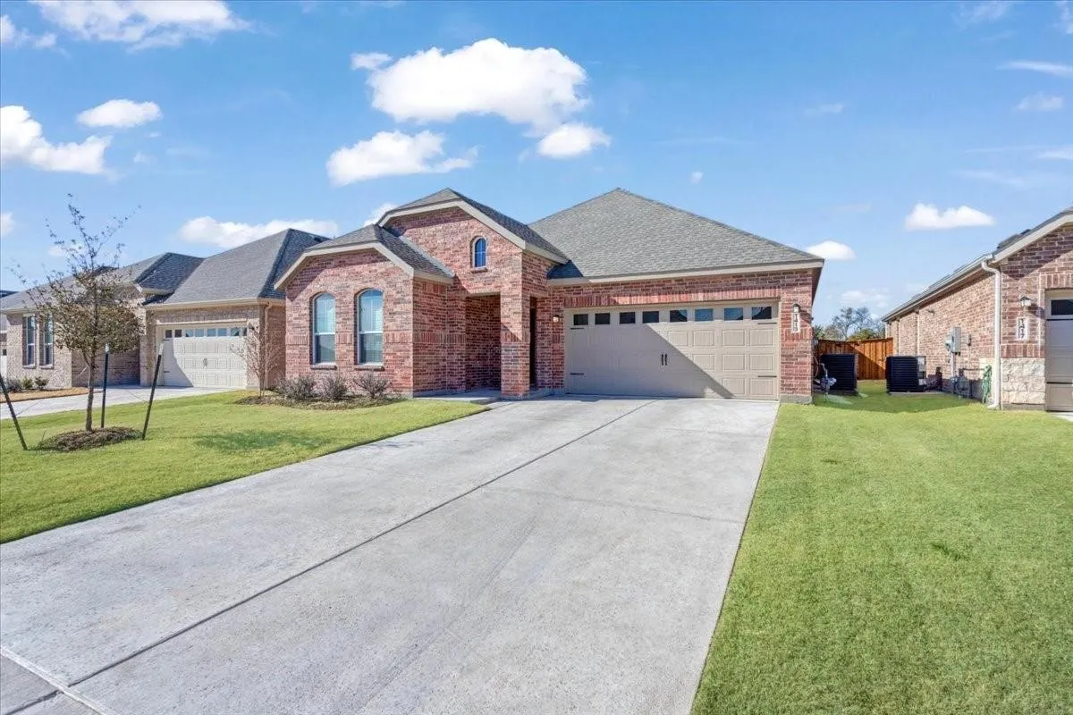 Brick exterior with arched windows, an attached garage, and a concrete driveway