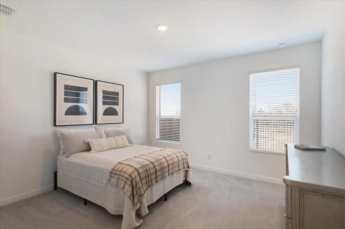 Recessed lighting illuminates this room featuring light-toned walls and two windows fitted with horizontal blinds