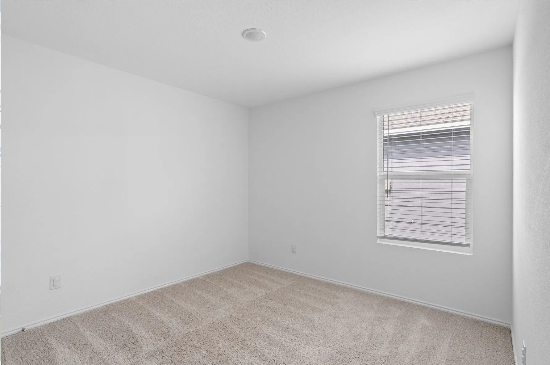 Neutral-toned carpeting, white walls, recessed lighting, and a single window with blinds