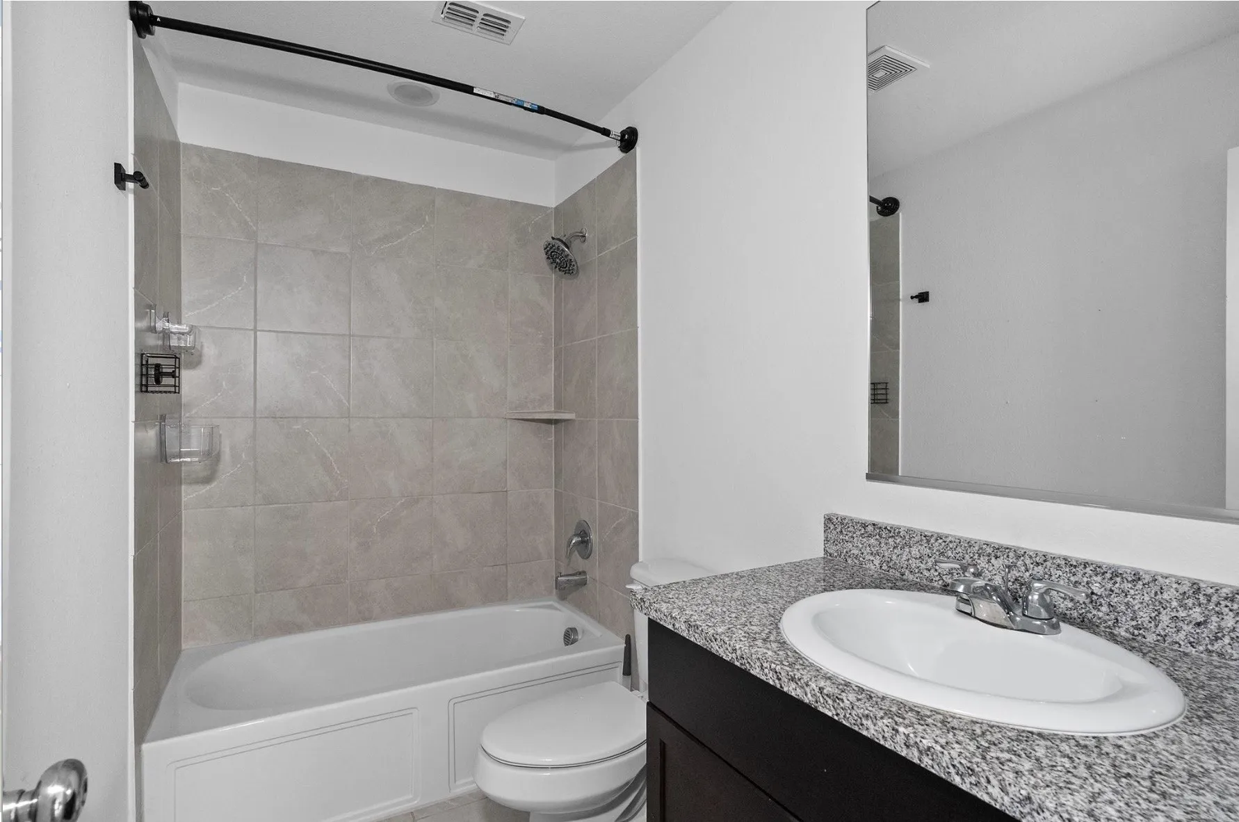 Bathtub with light gray wall tiling and a built-in shelf