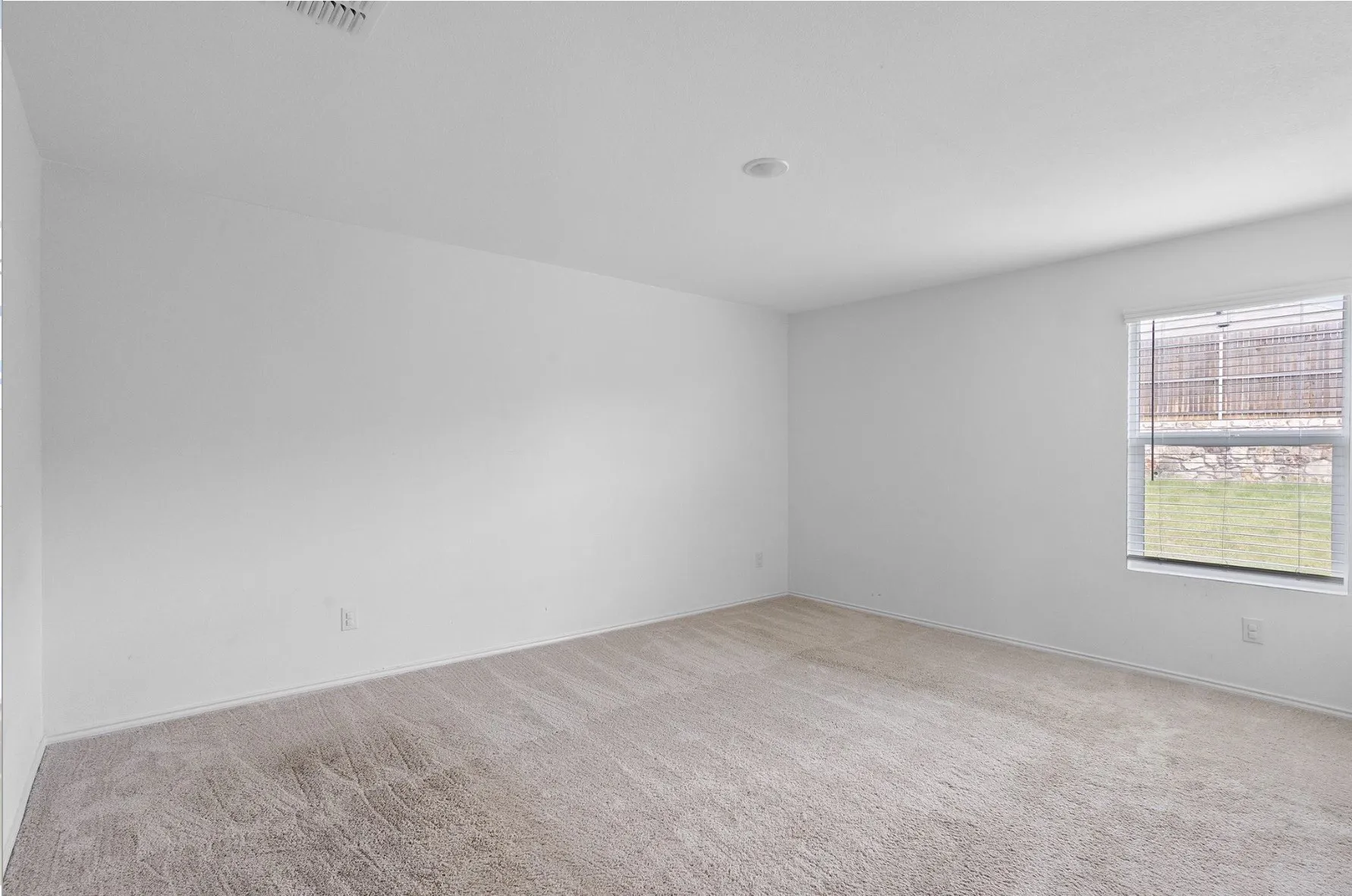 Recessed lighting, neutral wall paint, carpet flooring, and a single window with blinds