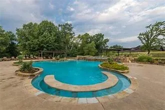 Freeform swimming pool with integrated spa and stone coping