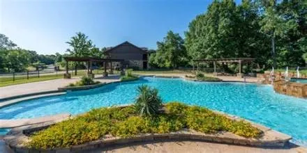 Expansive outdoor pool with integrated spa, stone coping, and surrounding pergolas
