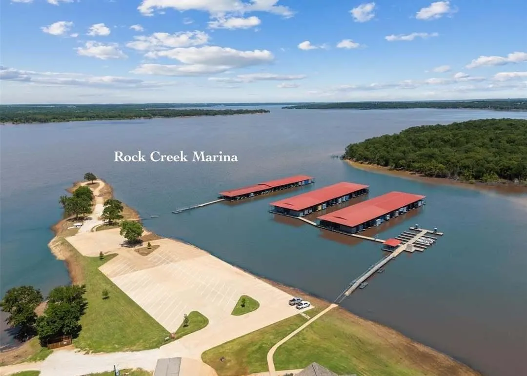 Marina with multiple covered boat slips and an expansive paved parking area