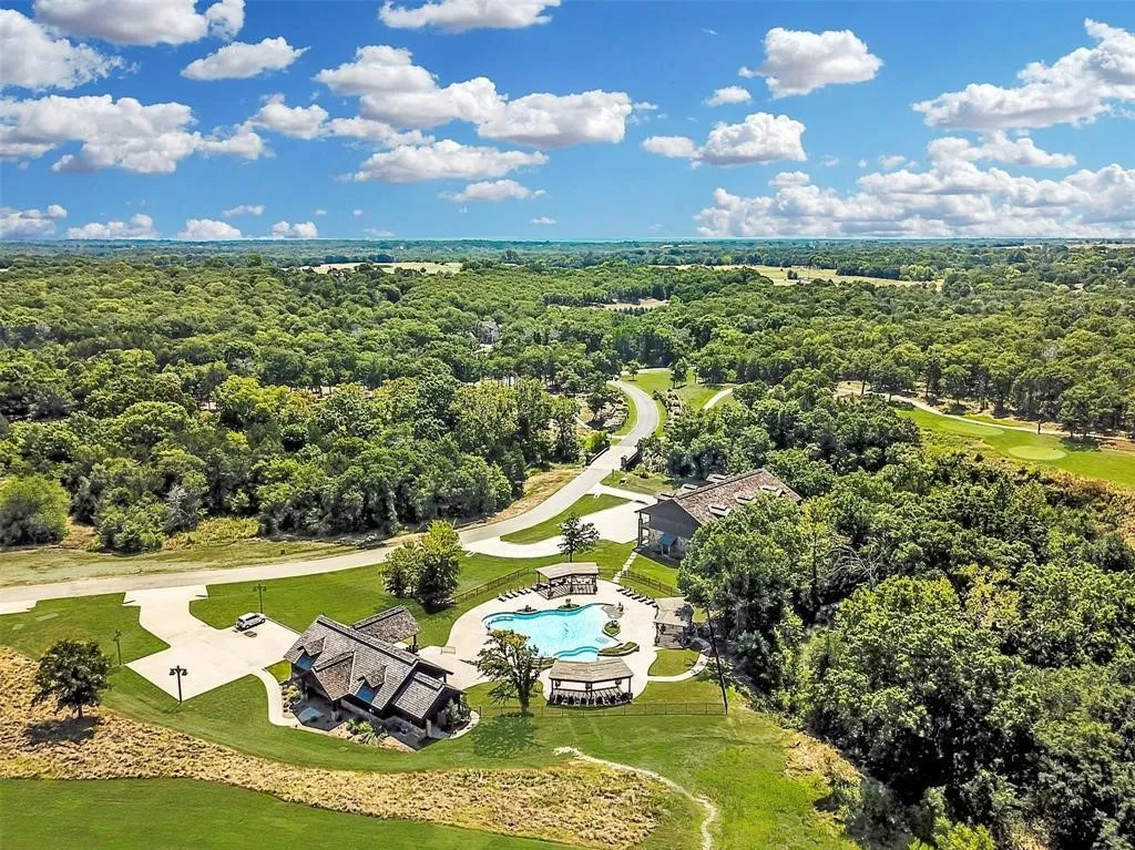 Expansive property featuring a large residence with multiple gabled roofs, a separate building with a covered outdoor area, a resort-style swimming pool, a covered gazebo, and a paved circular driveway