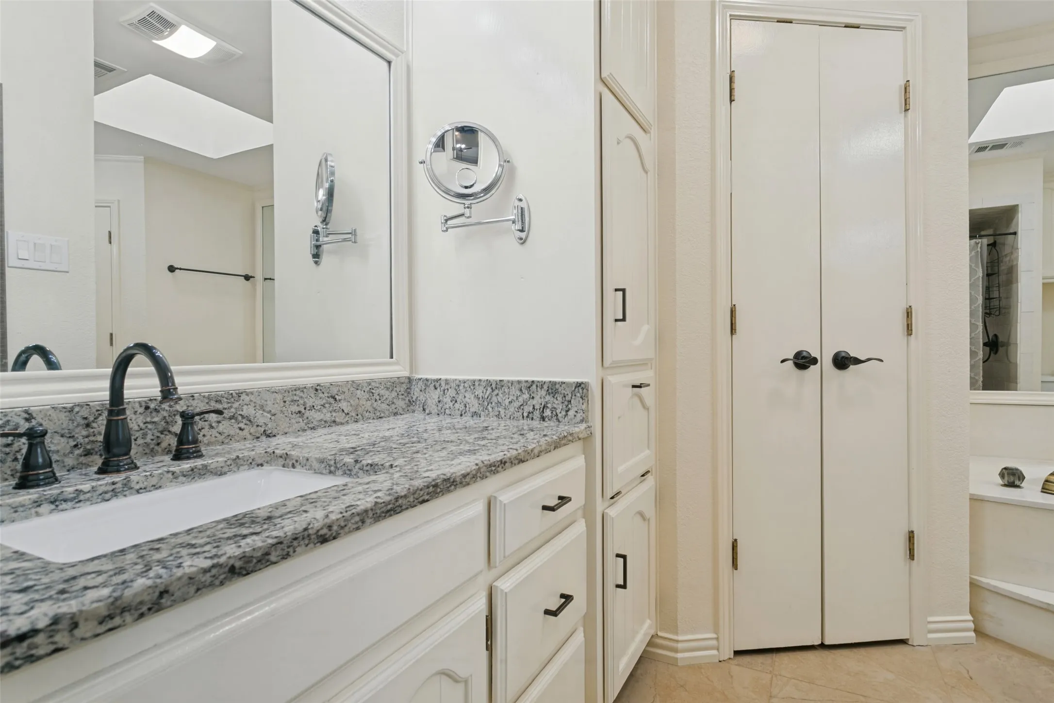 White vanity with an integrated sink, granite-style countertop, and dark-finish faucet