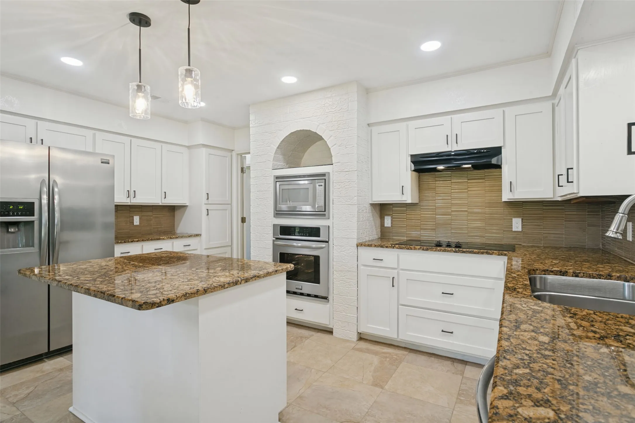 Kitchen featuring a center island with a stone countertop, white cabinetry with dark hardware, stainless steel appliances, and tile flooring