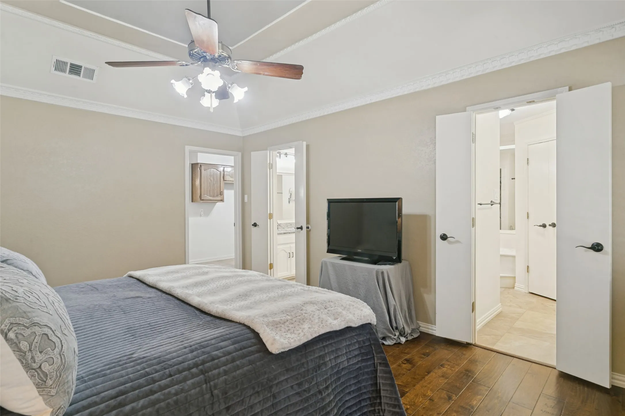 Hardwood-finish flooring, recessed ceiling, crown molding, double doors, and a ceiling fan with integrated lighting