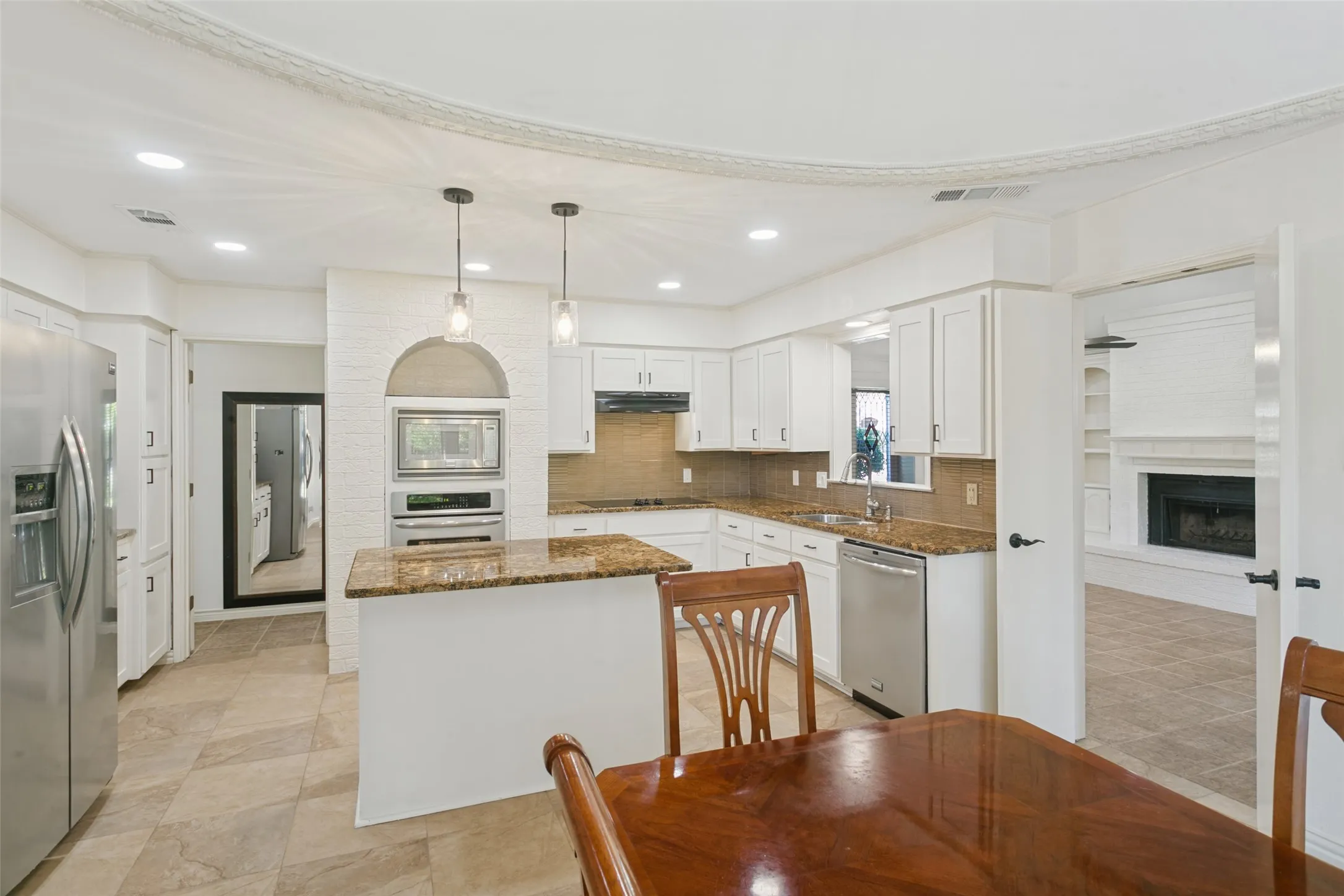 Spacious kitchen featuring an island, granite countertops, stainless steel appliances, recessed lighting, and tile flooring