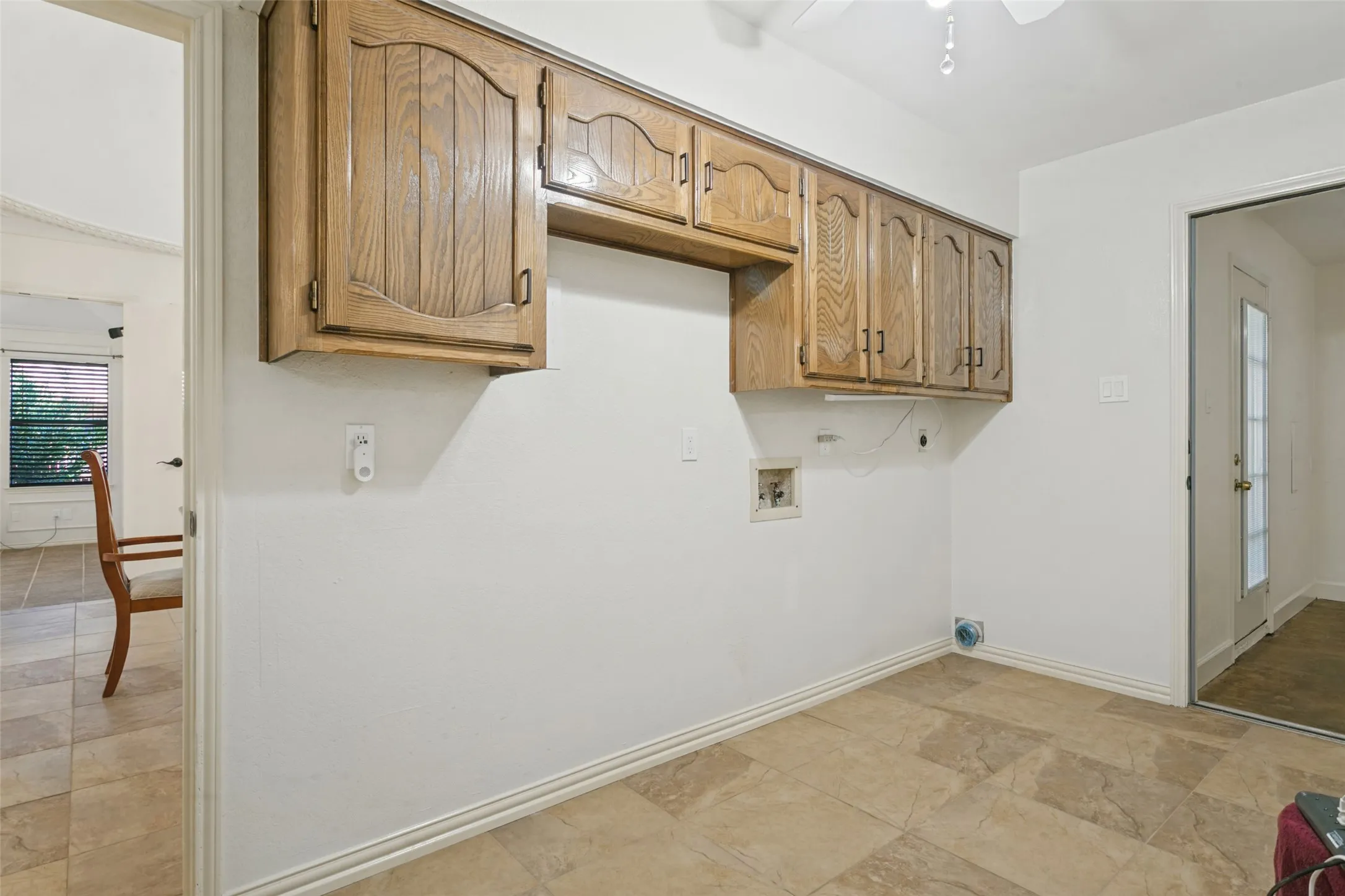 Laundry area featuring wood-finish cabinetry, tile flooring, and a ceiling fan
