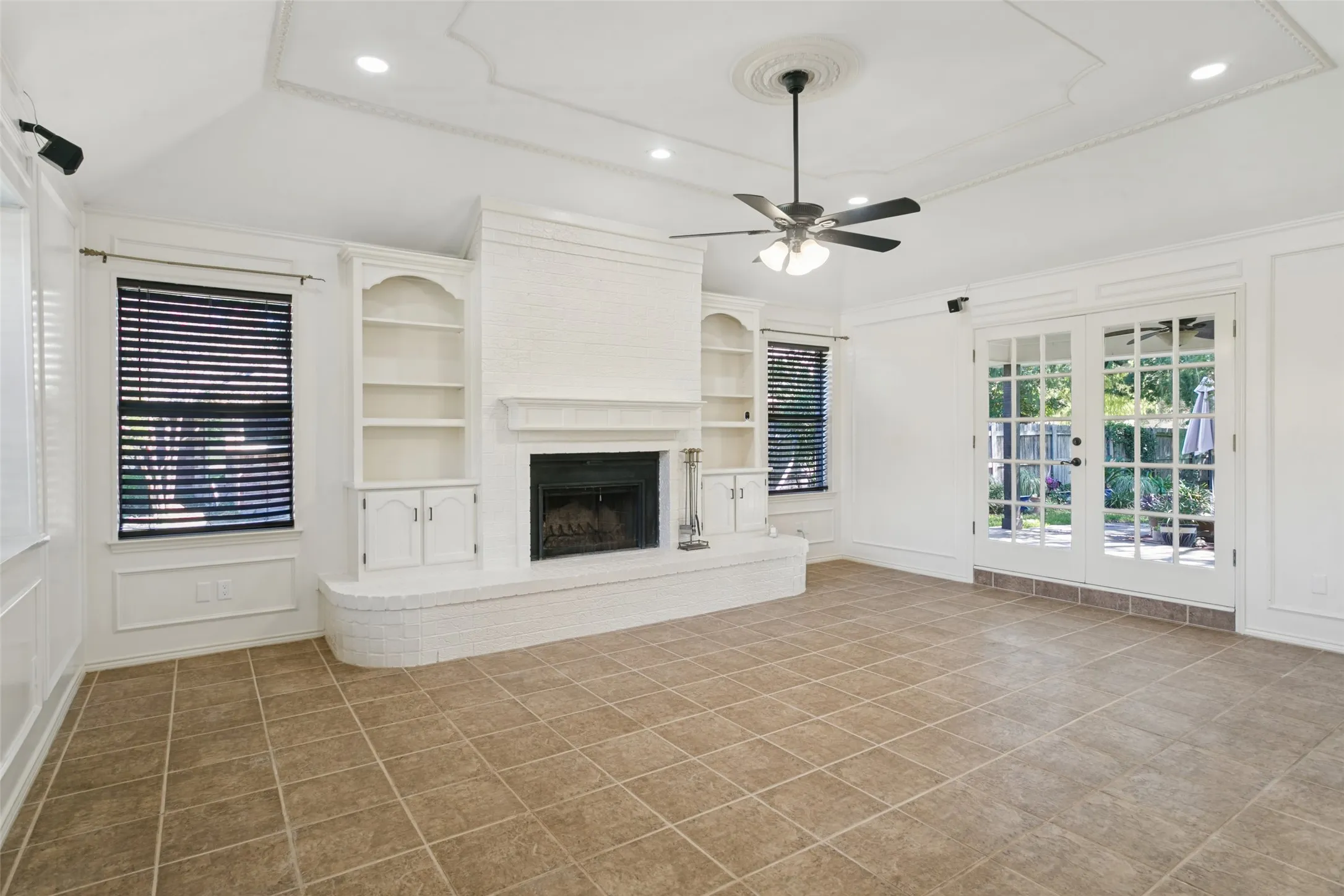 White-painted brick fireplace with hearth, built-in shelving, and tile flooring