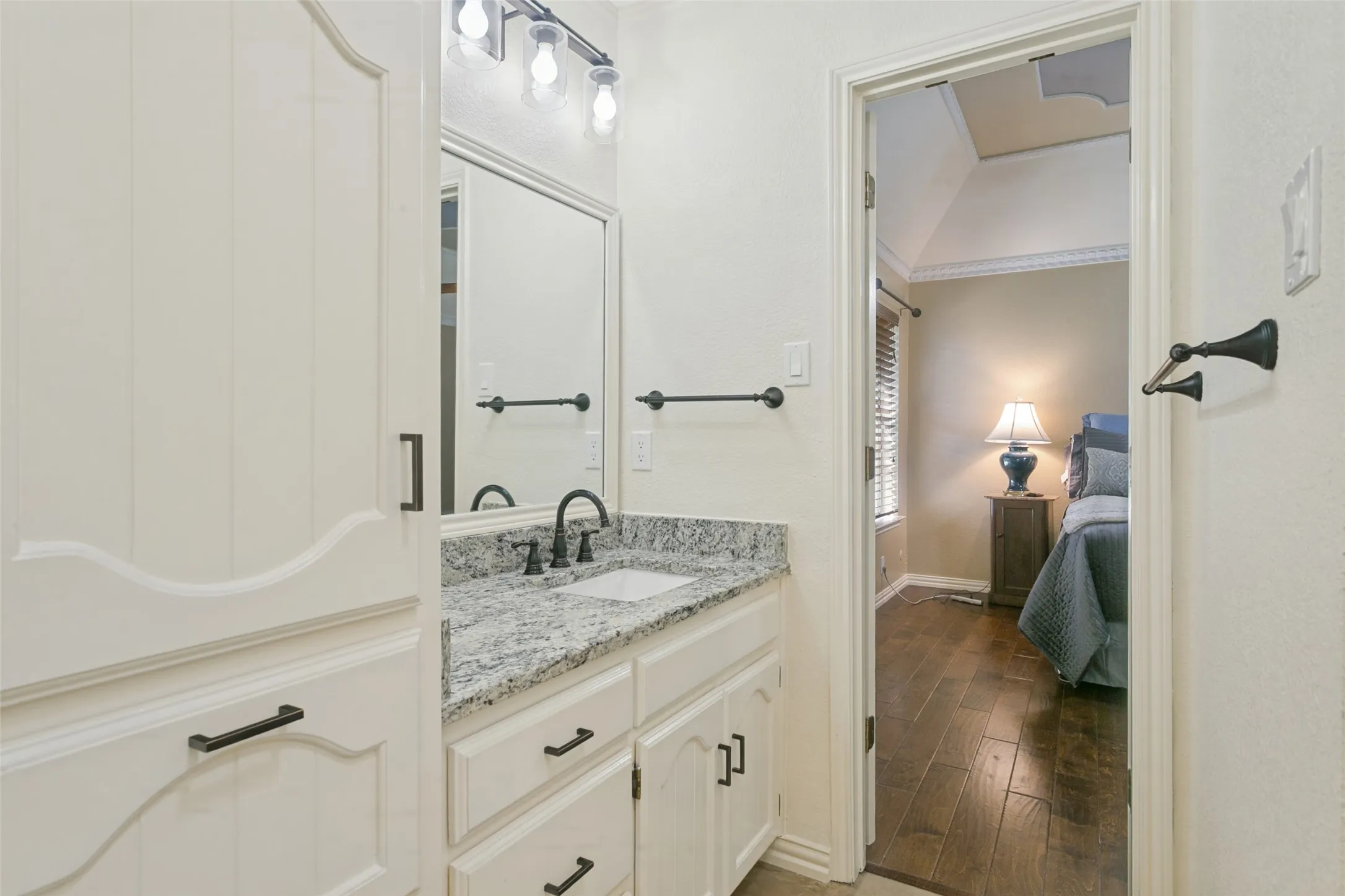 Bathroom featuring a white vanity with granite-style countertop, undermount sink, and black-finish hardware