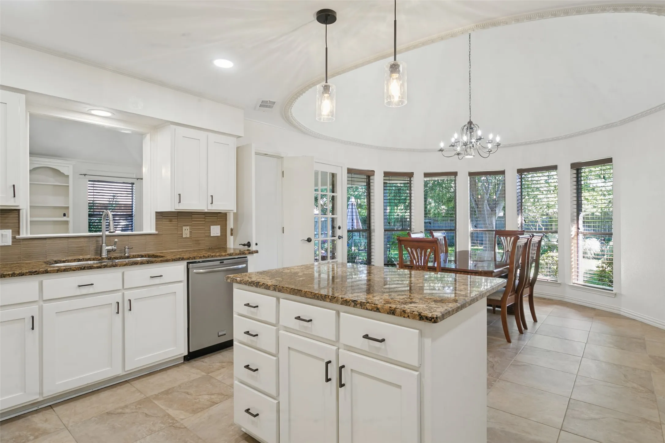 White cabinetry, stainless steel appliances, granite countertops, tile flooring, and a domed ceiling with decorative molding