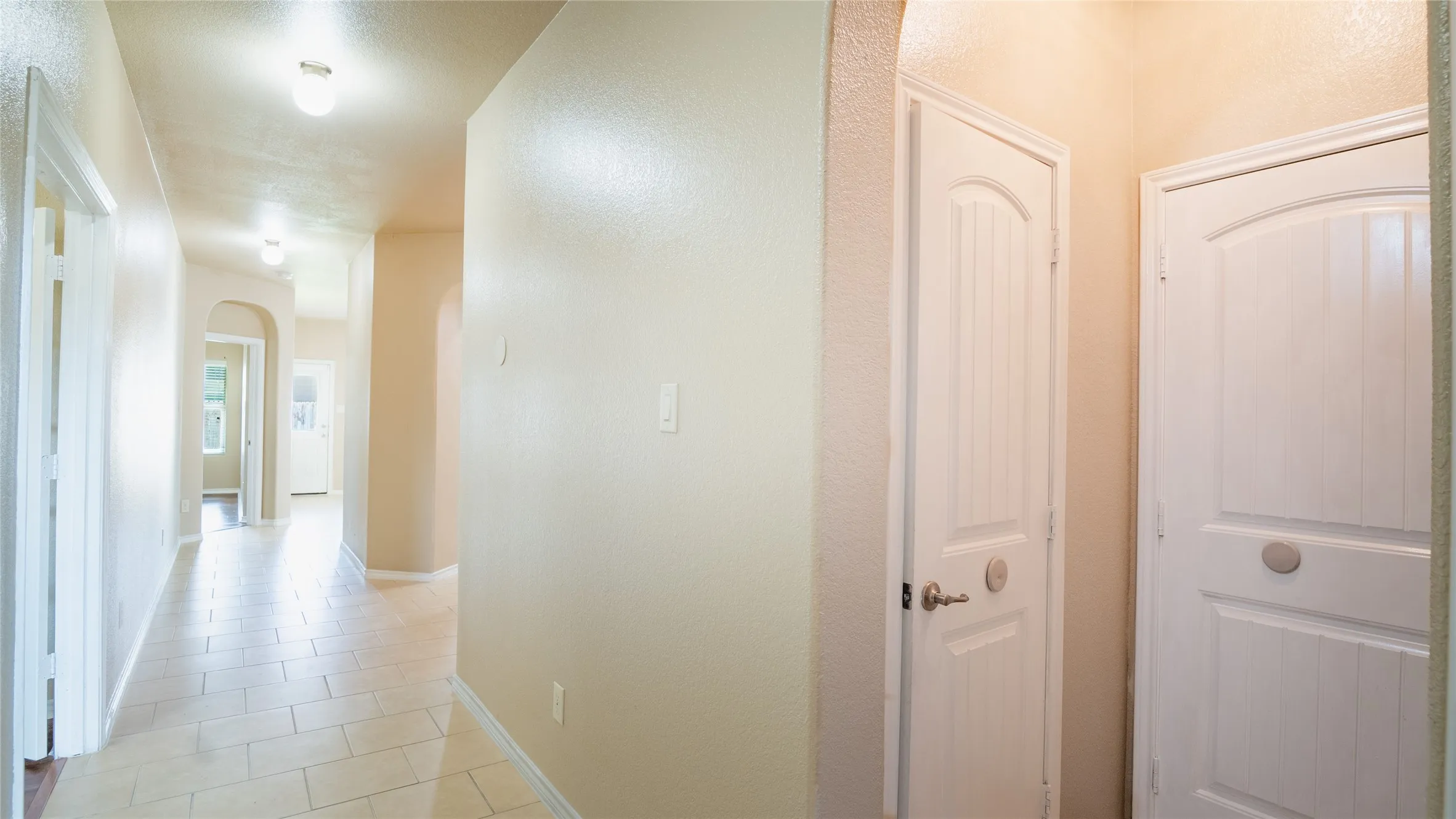 Hallway featuring tile flooring, arched doorways, and recessed lighting