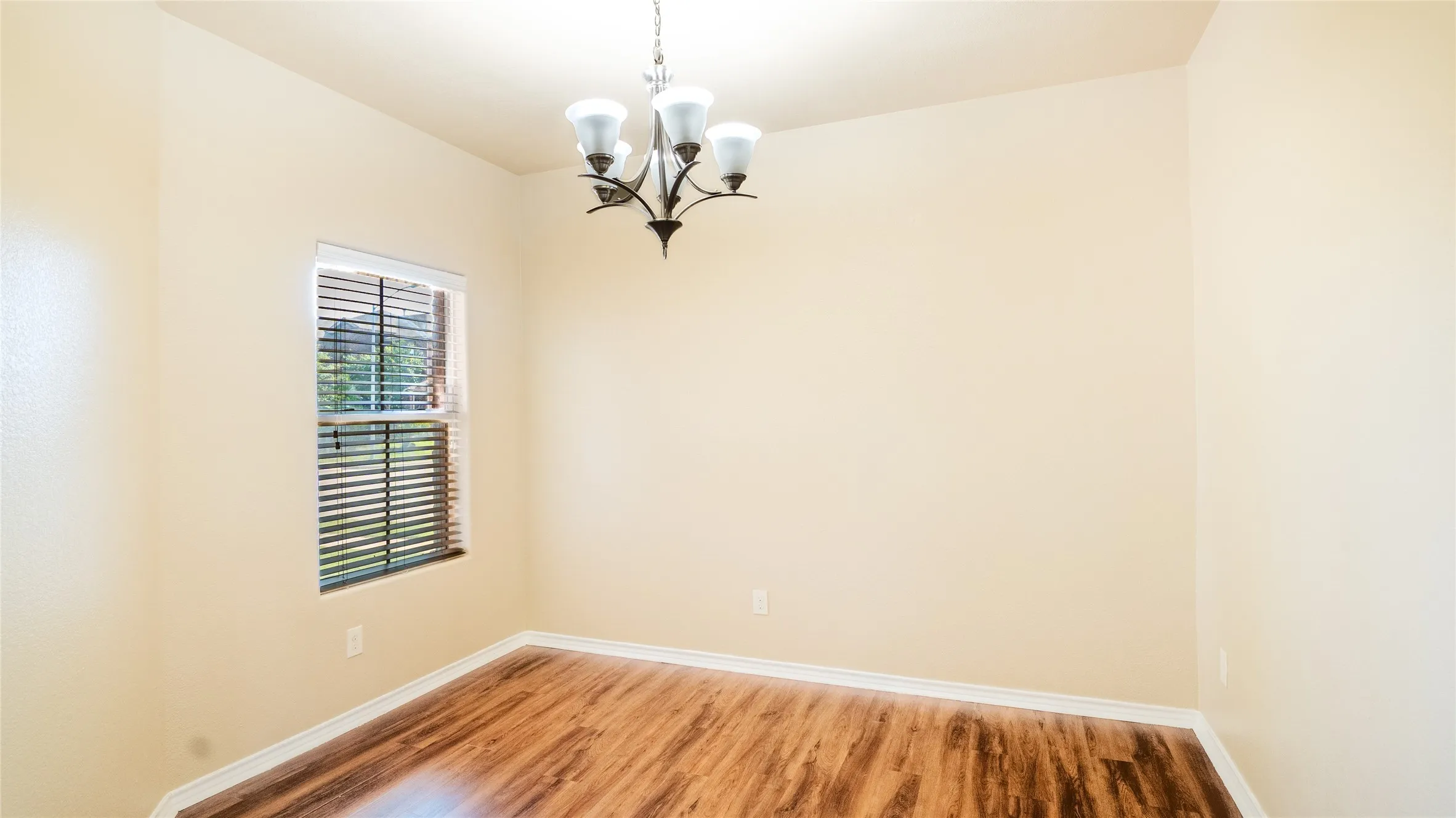 Wood-finish flooring, single window with blinds, and a built-in chandelier
