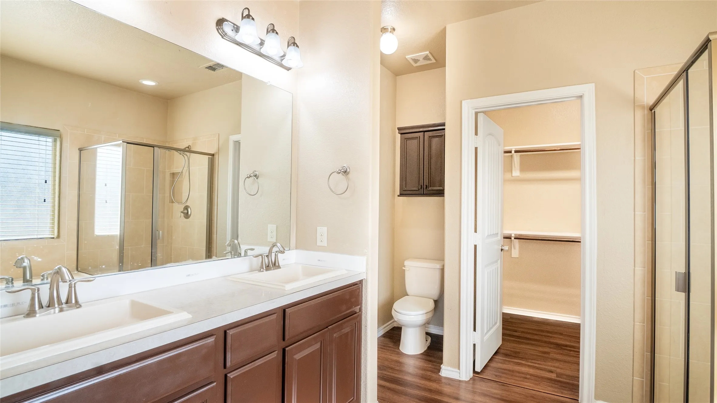 Dual vanity with integrated sinks, wood-finish cabinetry, a framed mirror, and chrome fixtures
