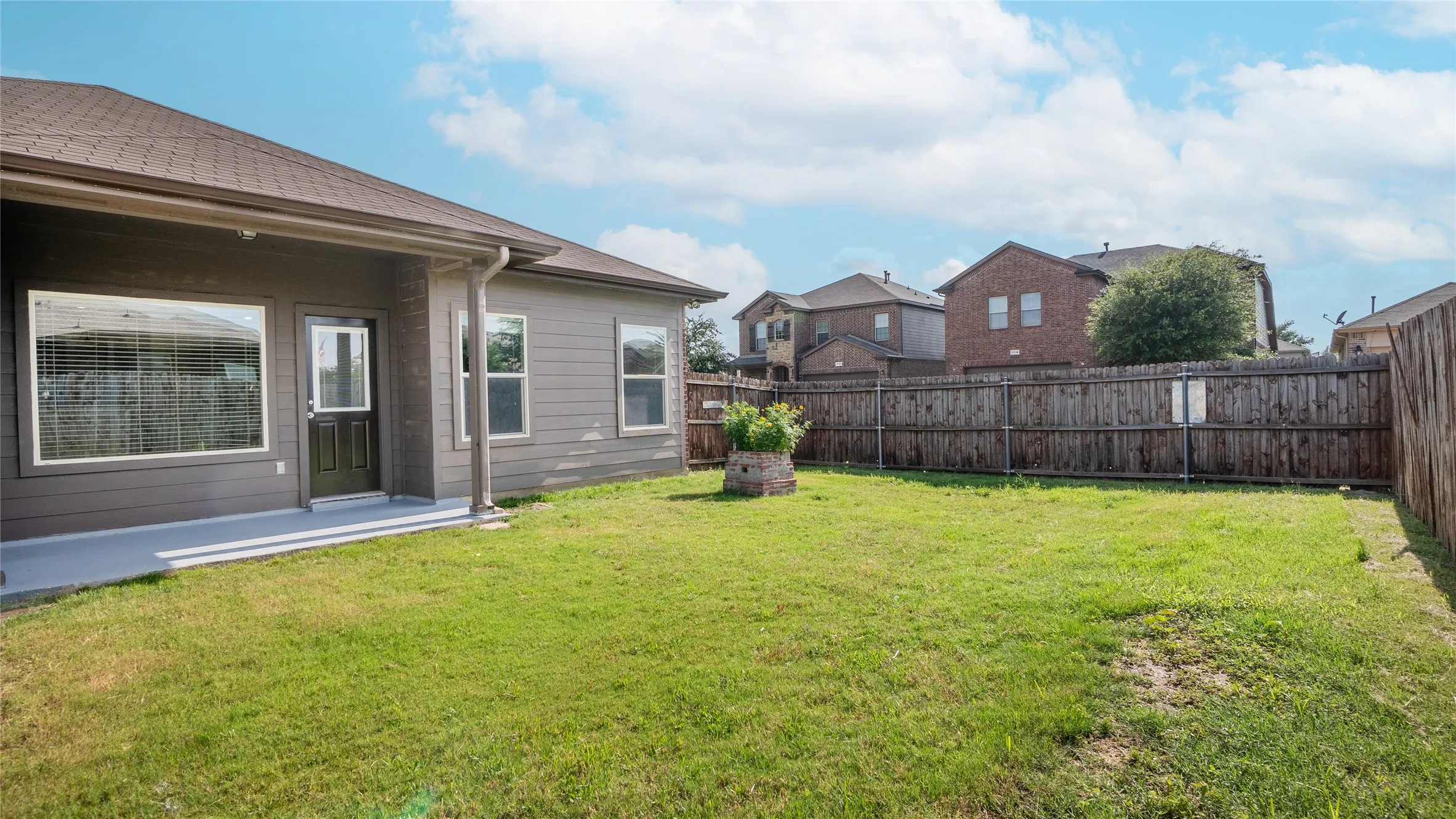 Expansive backyard with a covered patio, manicured lawn, and wooden privacy fencing