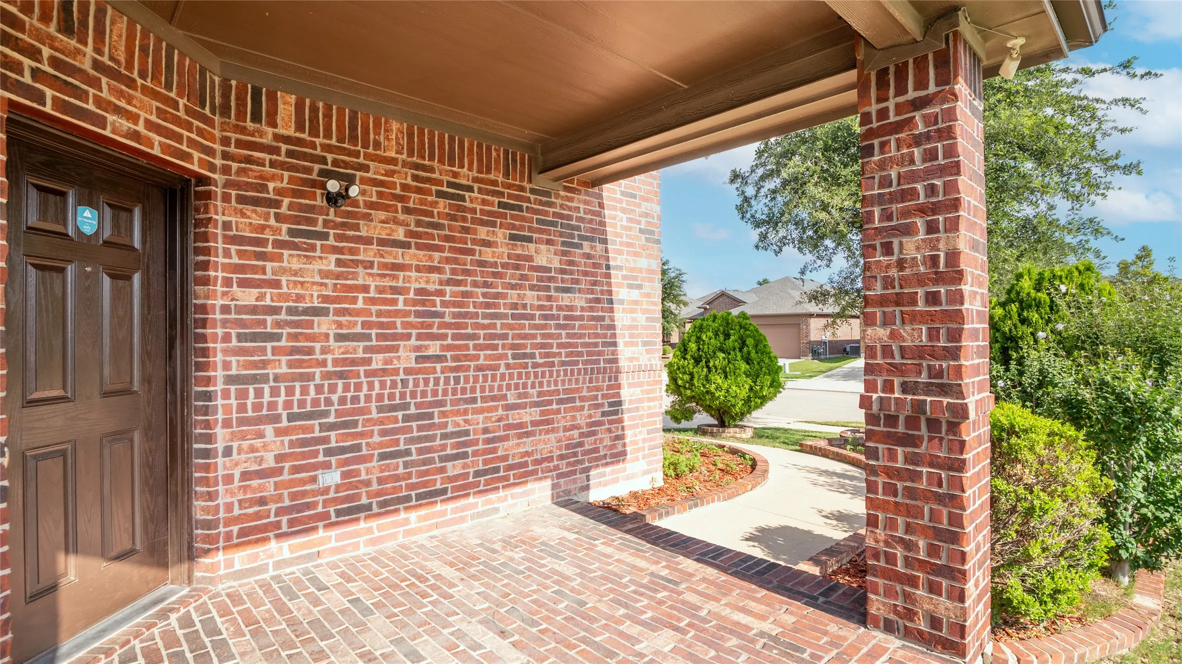 Brick exterior with covered porch, paneled entry door, and brick flooring