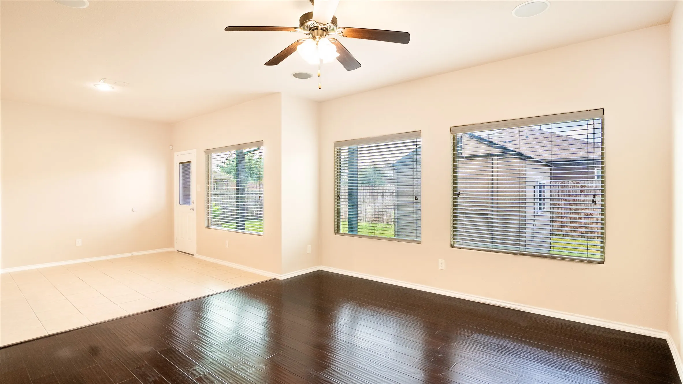 Wood-finish flooring, tiled flooring, ceiling fan, multiple windows, and a glass-paneled door