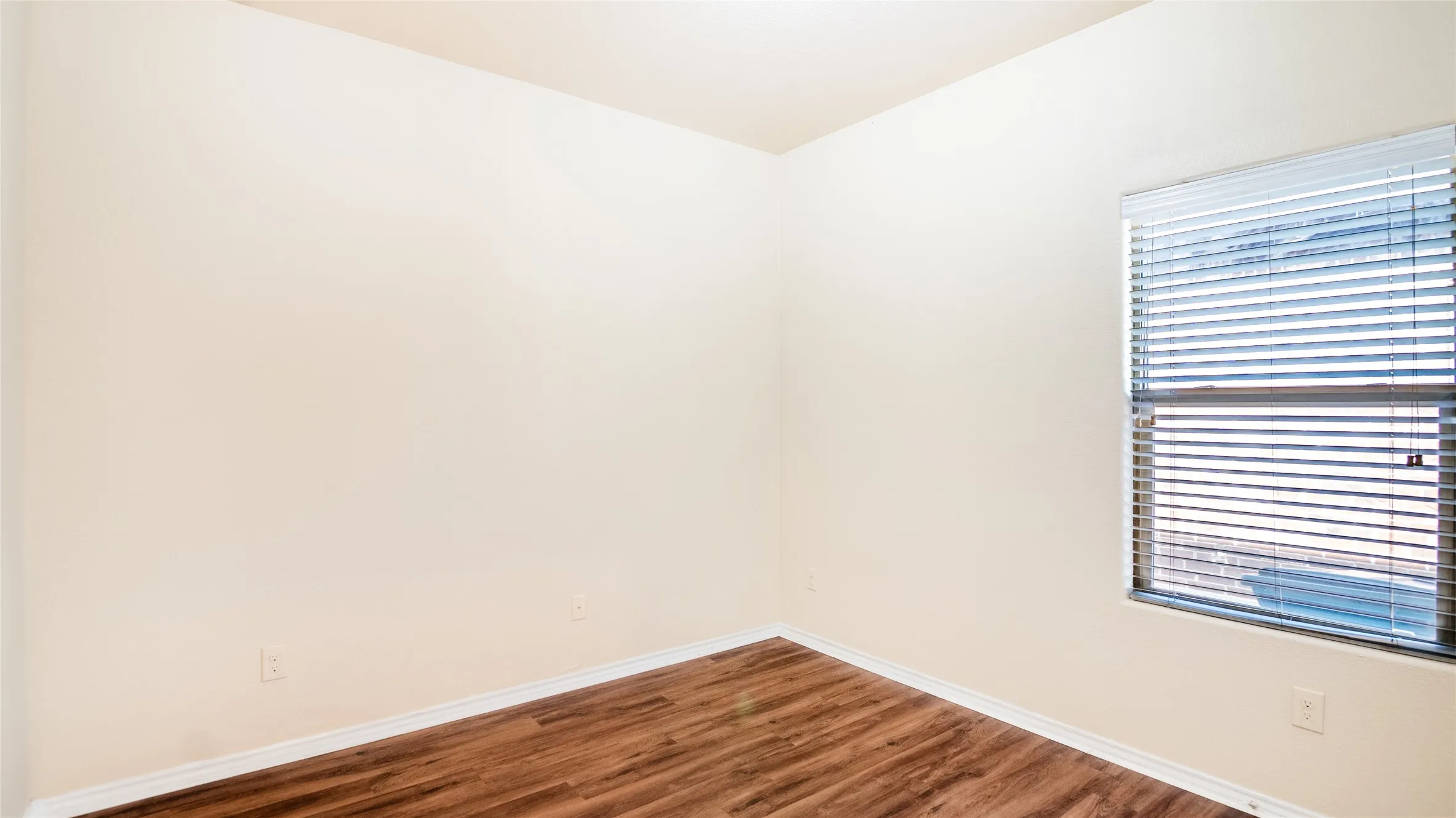 Wood-finish flooring, neutral wall tones, and a window with blinds