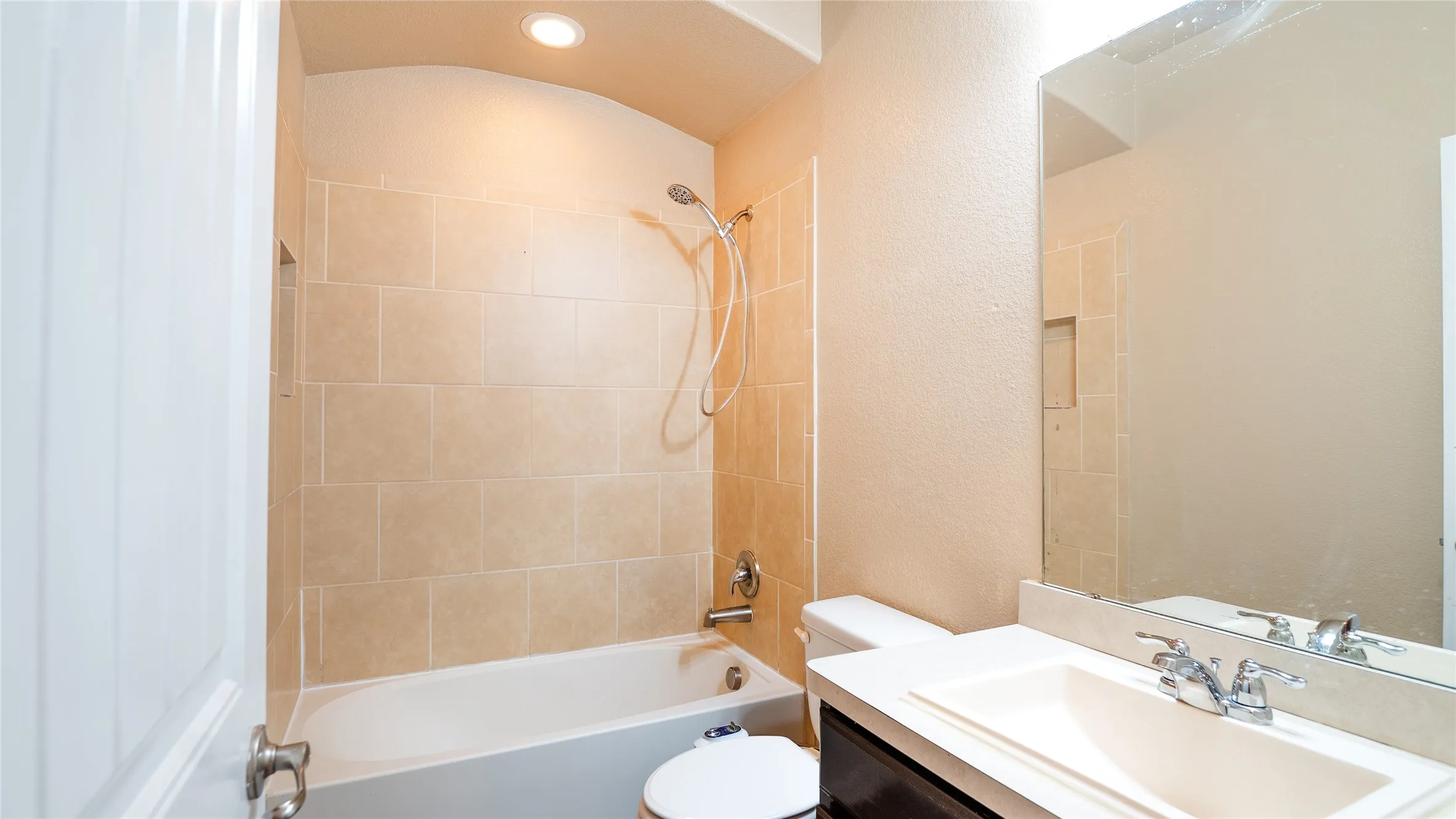 Bathtub with tile surround, built-in shower niche, and a wall-mounted showerhead