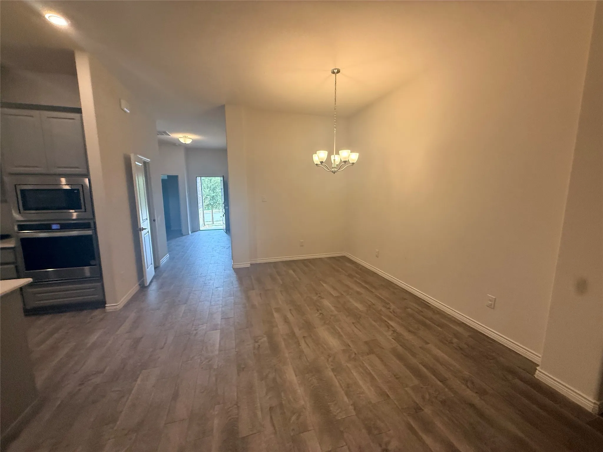 Wood-finish flooring throughout, with a contemporary chandelier and recessed lighting
