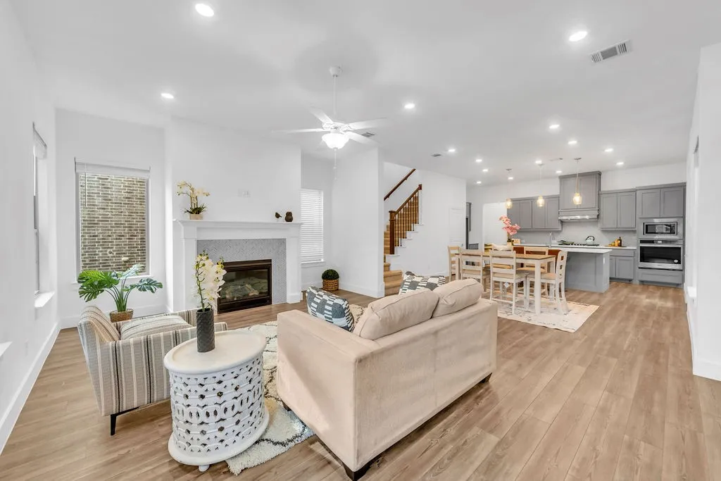 Open-concept living area with wood-finish flooring, recessed lighting, and a white ceiling fan