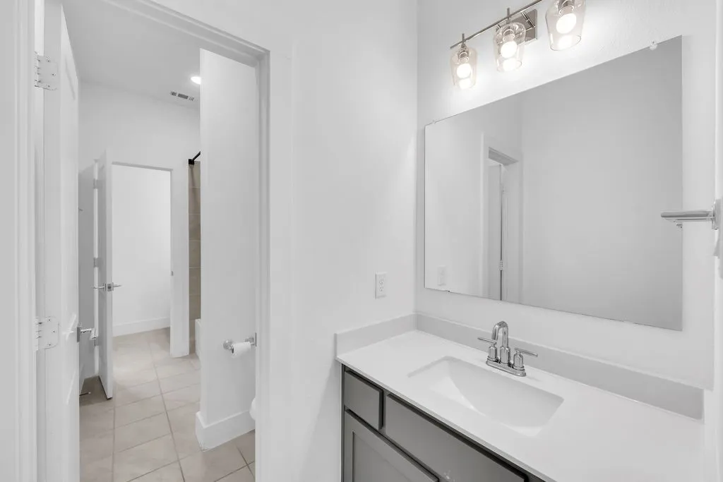 Vanity with a polished chrome faucet, white countertop, and gray cabinetry