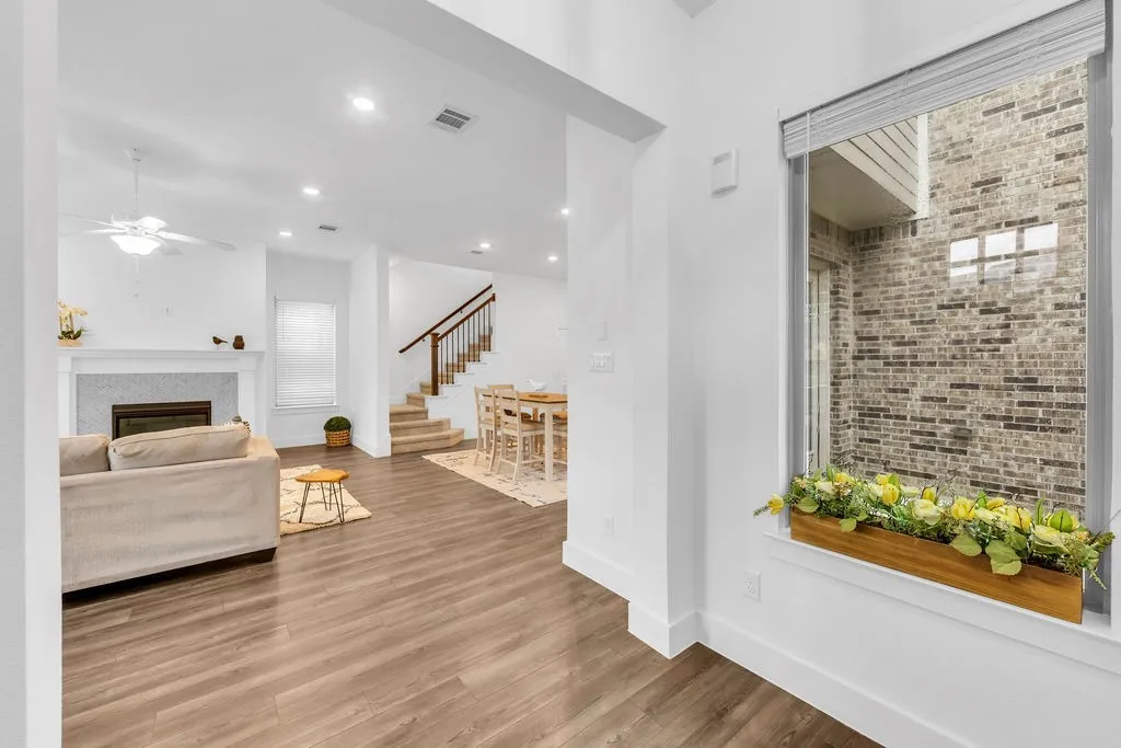 Recessed lighting, wood-finish flooring, white trim, and a fireplace with a stone surround