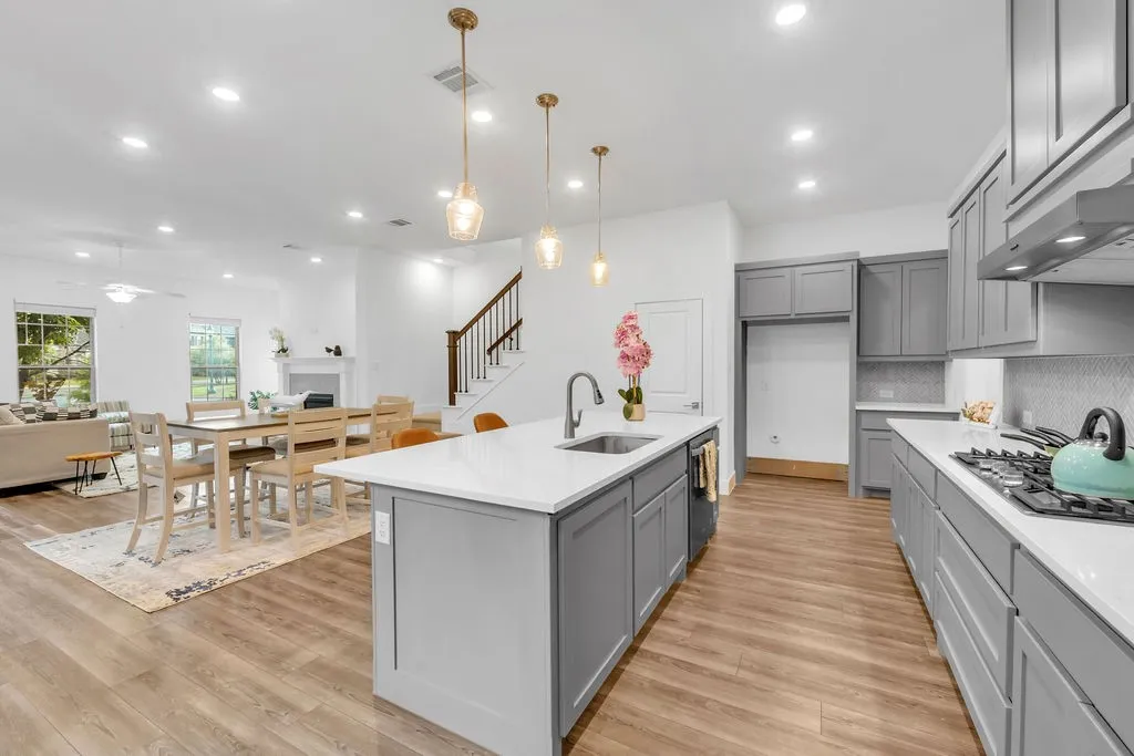 Kitchen featuring a center island, gray cabinetry, integrated sink, and white countertops