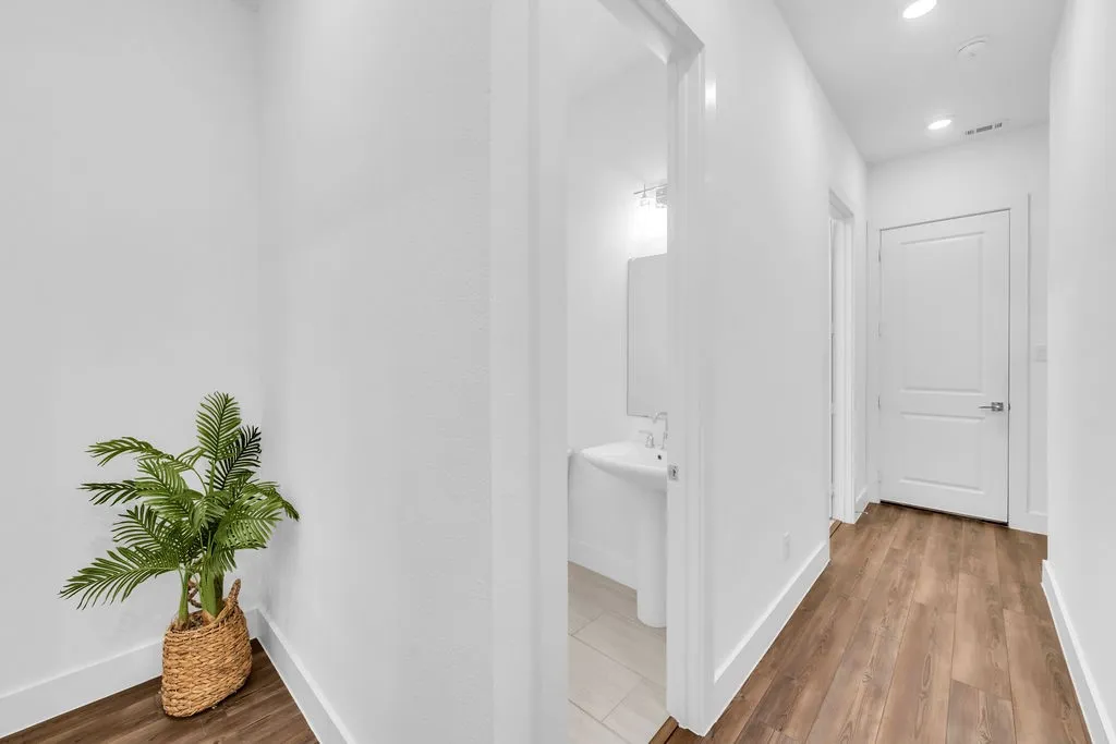 Hallway with wood-finish flooring, recessed lighting, and a white interior door