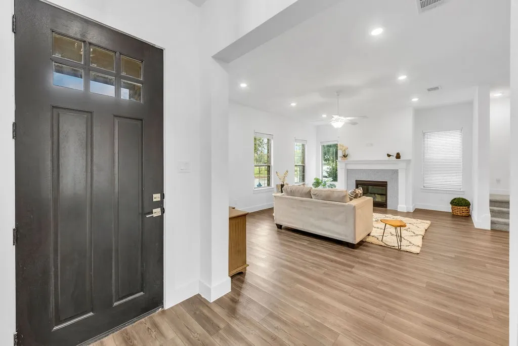 Entry door with multi-pane window, wood-finish flooring, recessed lighting, and white trim