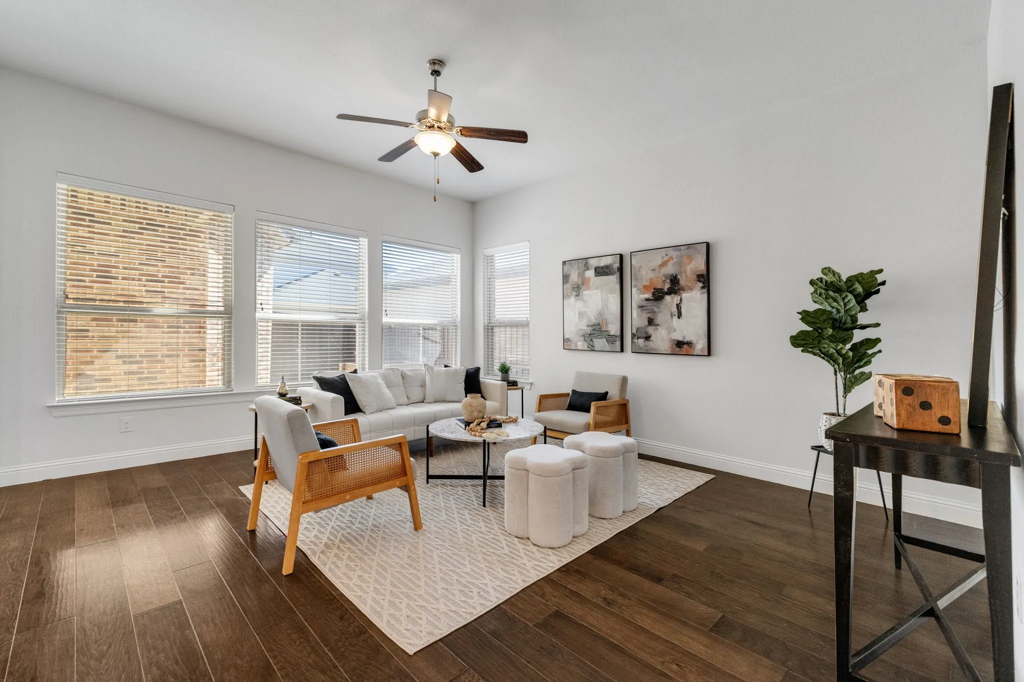 Wood-finish flooring, multiple windows with blinds, and a ceiling fan with integrated lighting