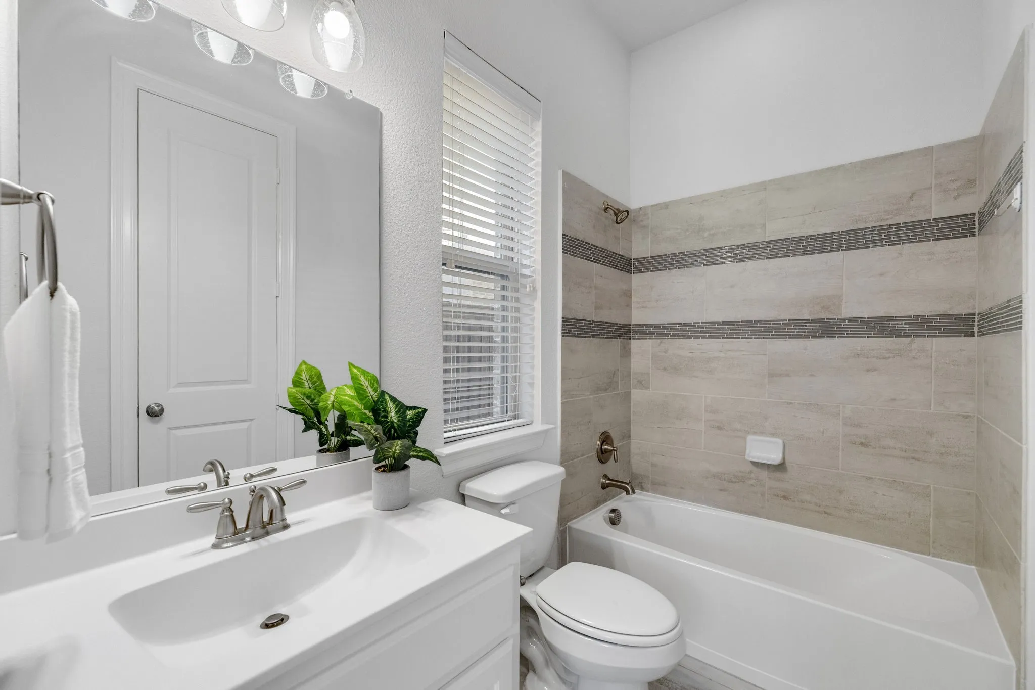 Downstairs bathroom White vanity with integrated sink, brushed nickel faucet, large mirror, and overhead lighting