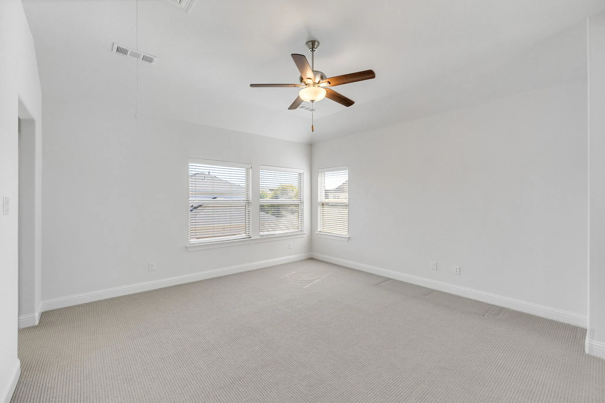 Secondary upstairs bedroom- Recessed lighting with a ceiling fan, multiple windows with blinds, and light-toned carpet flooring