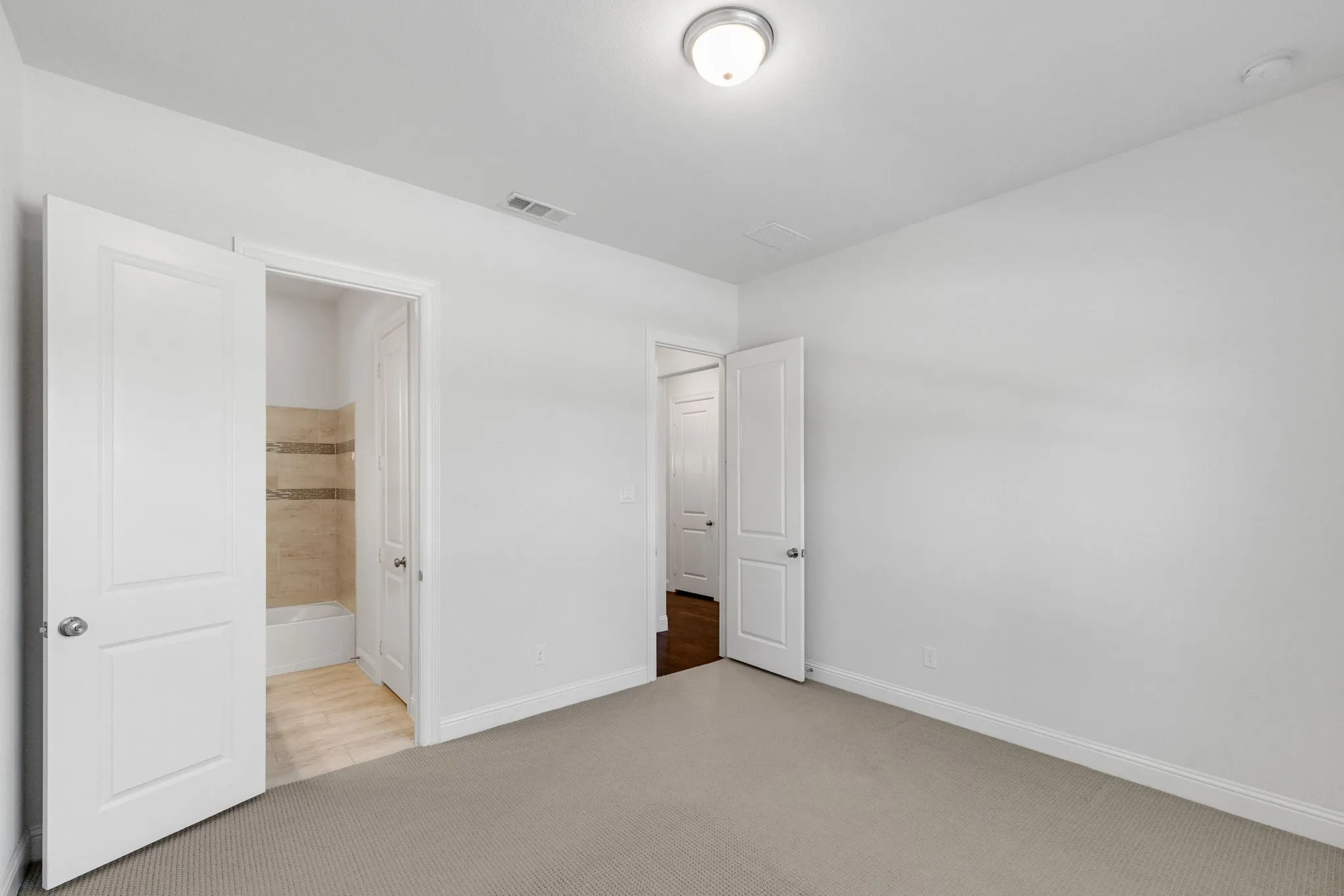 First floor bedroom/ Downstairs bedroom- Plush carpeting, neutral wall tones, interior panel doors, and overhead flush mount lighting