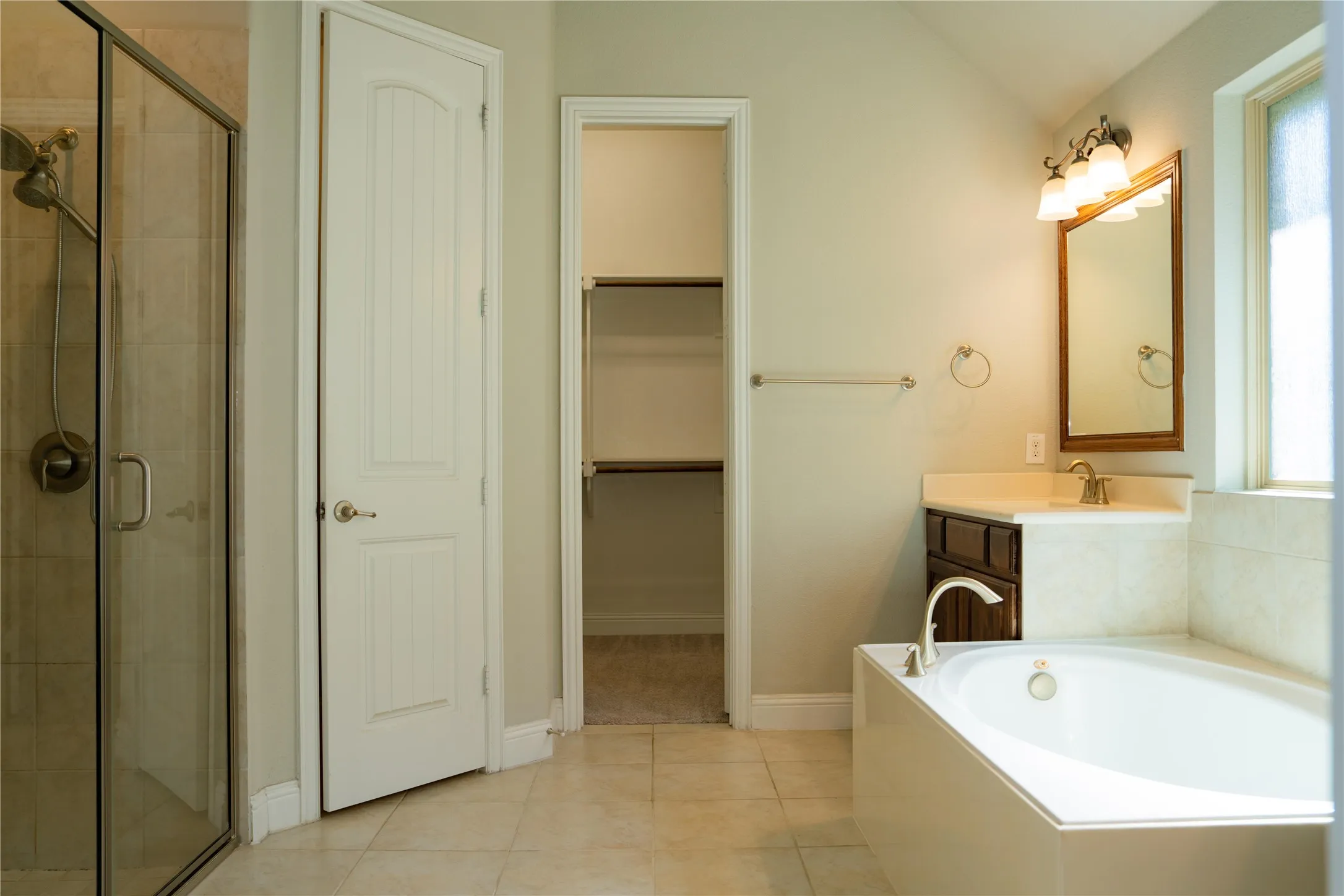 Bathroom with a walk-in shower, built-in soaking tub, a single vanity with a solid surface countertop, and tile flooring