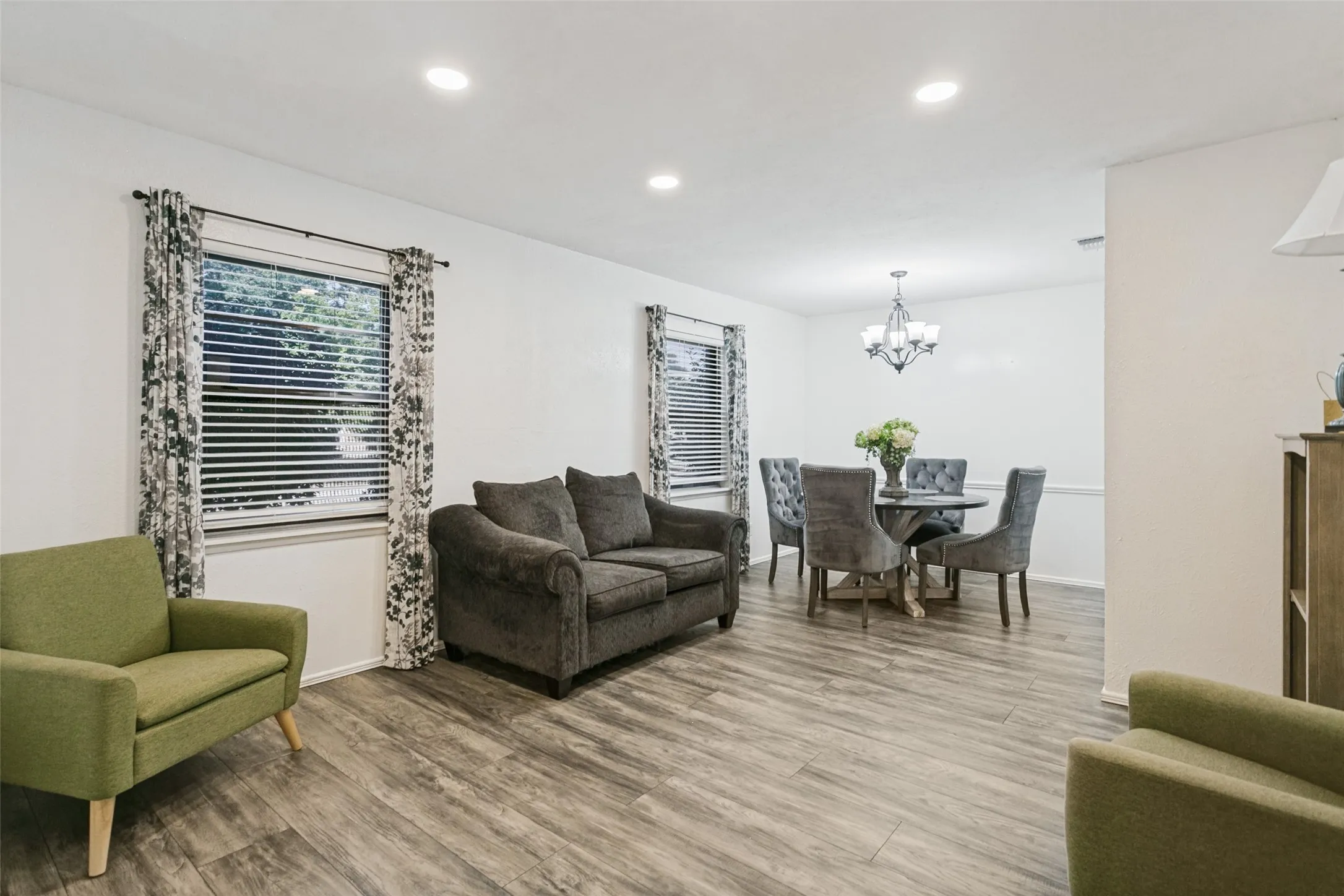 Wood-finish flooring throughout, recessed lighting, and a dining area with a chandelier