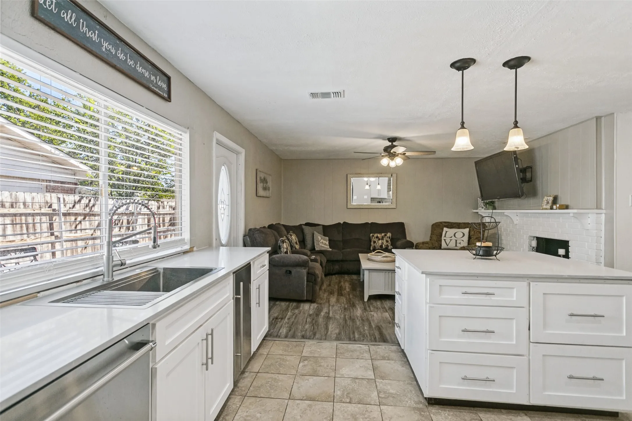 Kitchen featuring white cabinetry, light-toned countertops, a stainless steel sink, and a built-in dishwasher