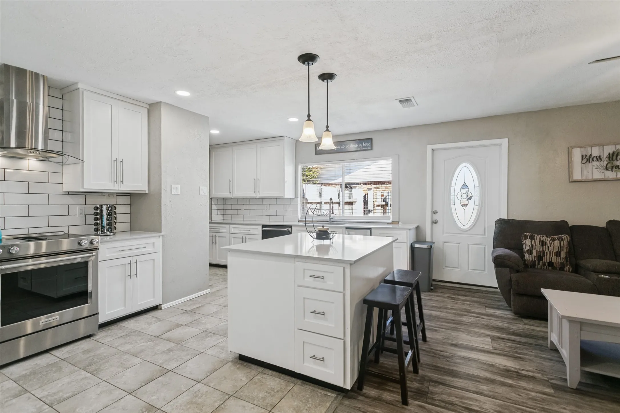 Kitchen featuring white shaker cabinetry, stainless steel appliances, subway tile backsplash, and a central island with a solid surface countertop