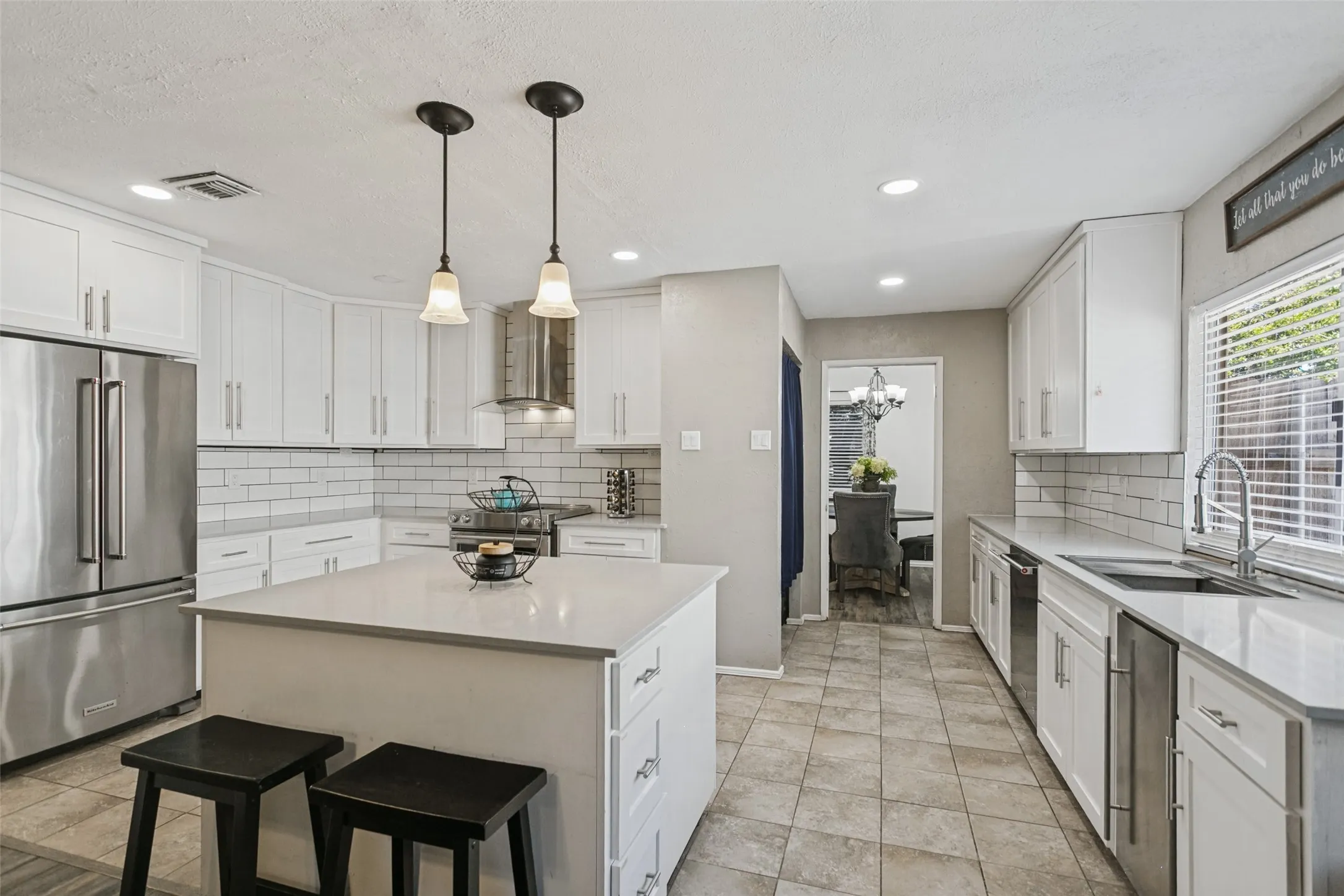 White shaker-style cabinetry, stainless steel appliances, a center island, subway tile backsplash, and recessed lighting