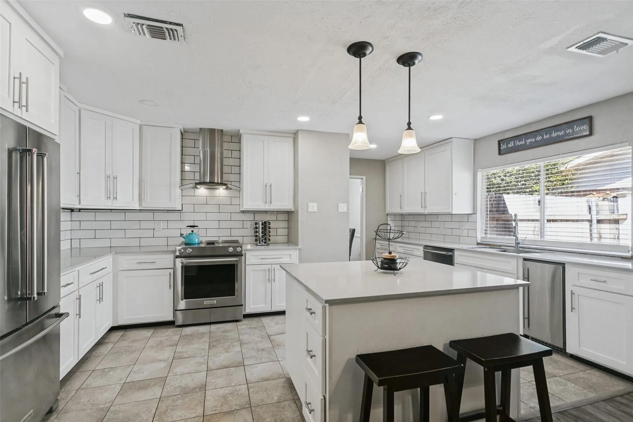 White cabinetry, stainless steel appliances, light-toned countertops, subway tile backsplash, and recessed lighting