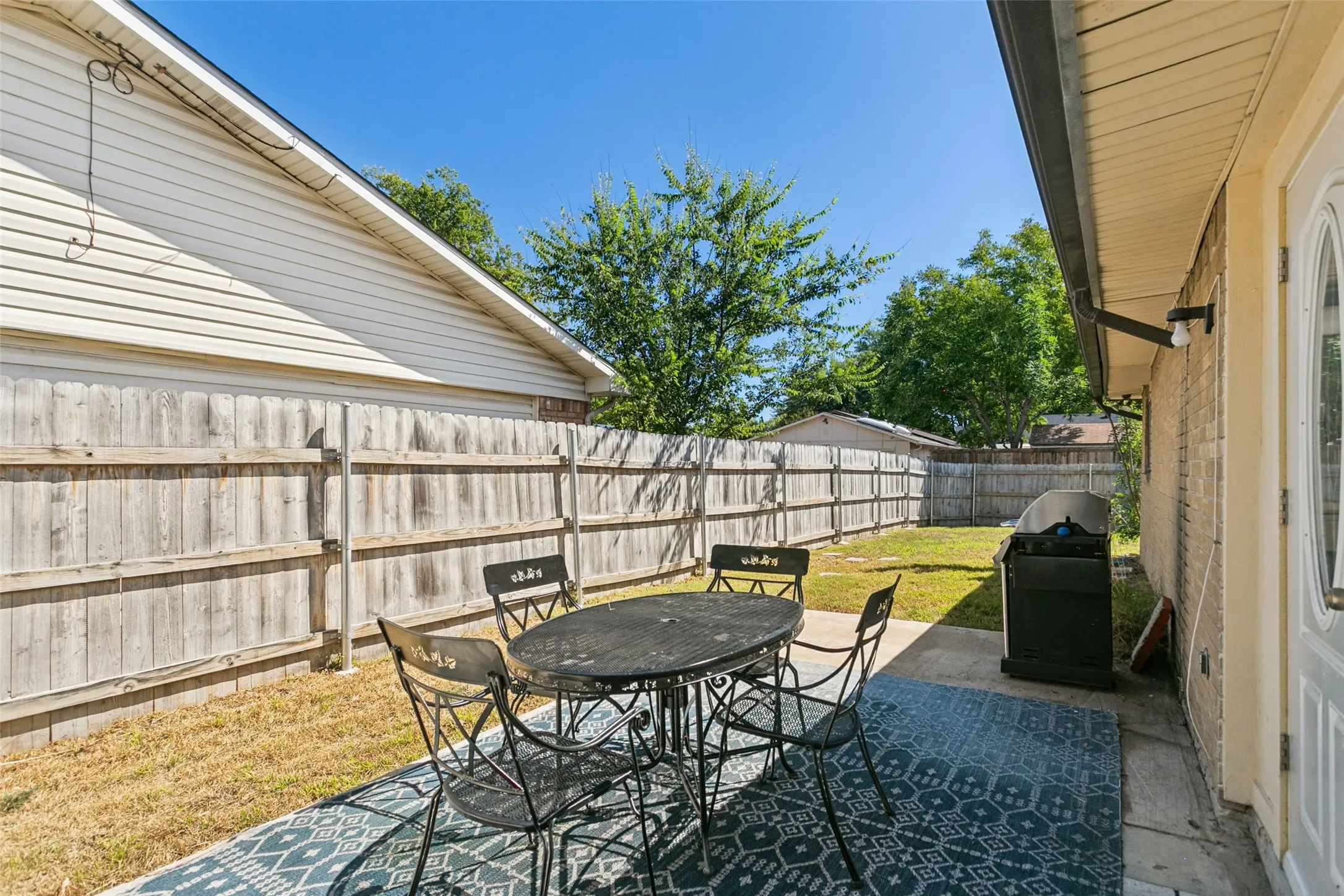 Private backyard featuring a concrete patio, wood fence, and mature trees