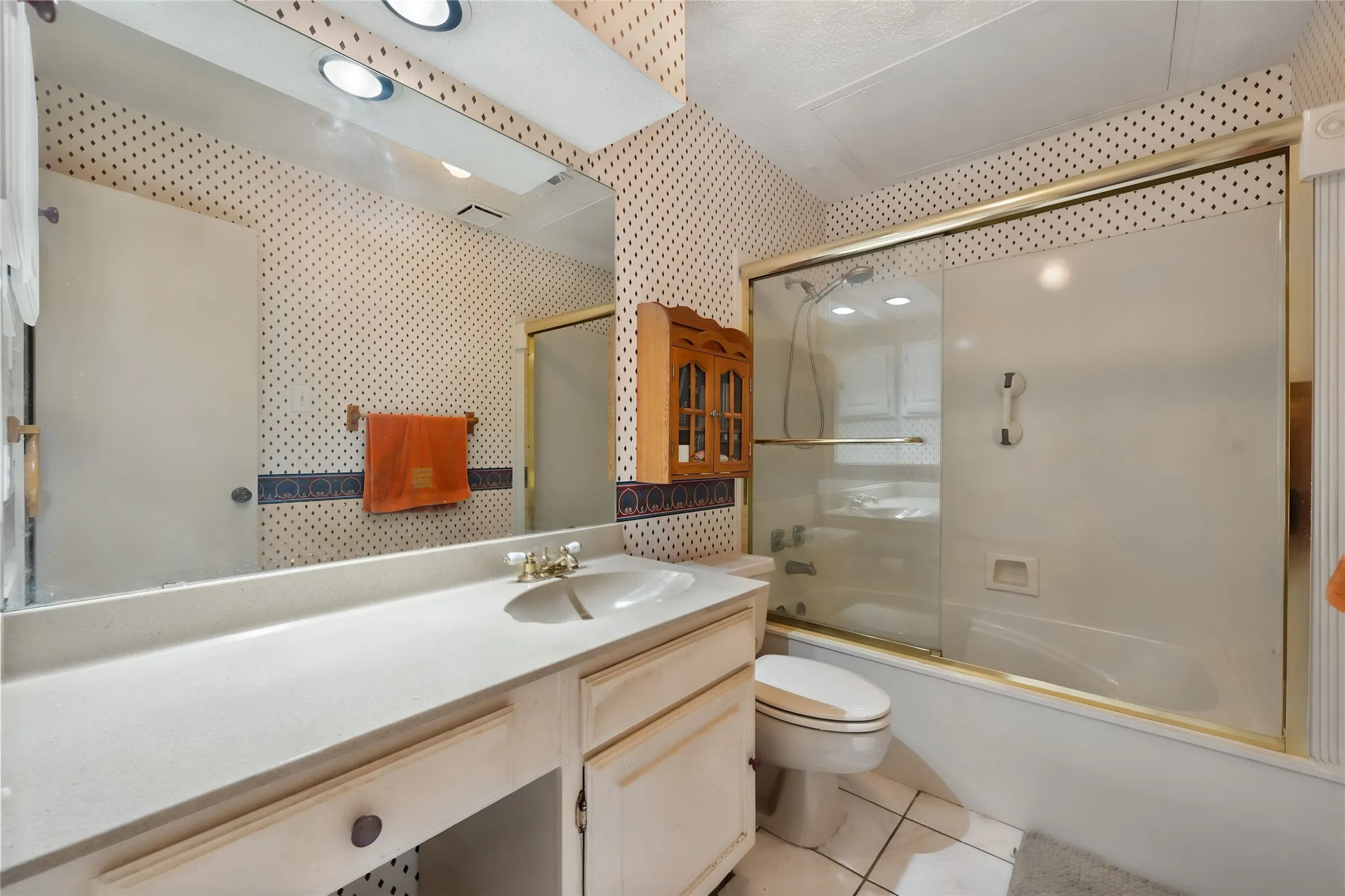 White vanity with integrated sink, brass-finish faucet, and expansive wall-mounted mirror