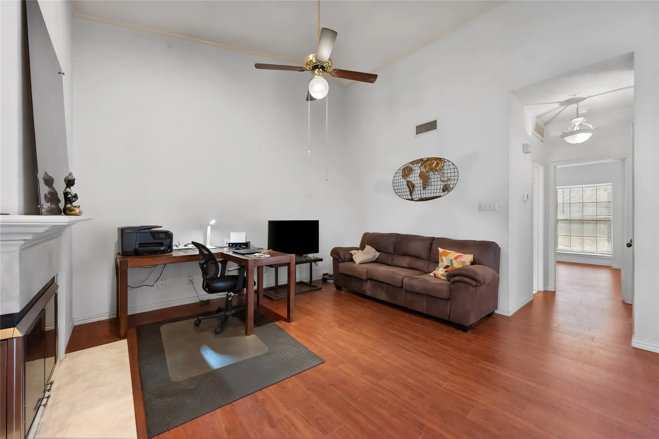 Vaulted ceiling with a ceiling fan, fireplace with a white mantel, and wood-finish flooring