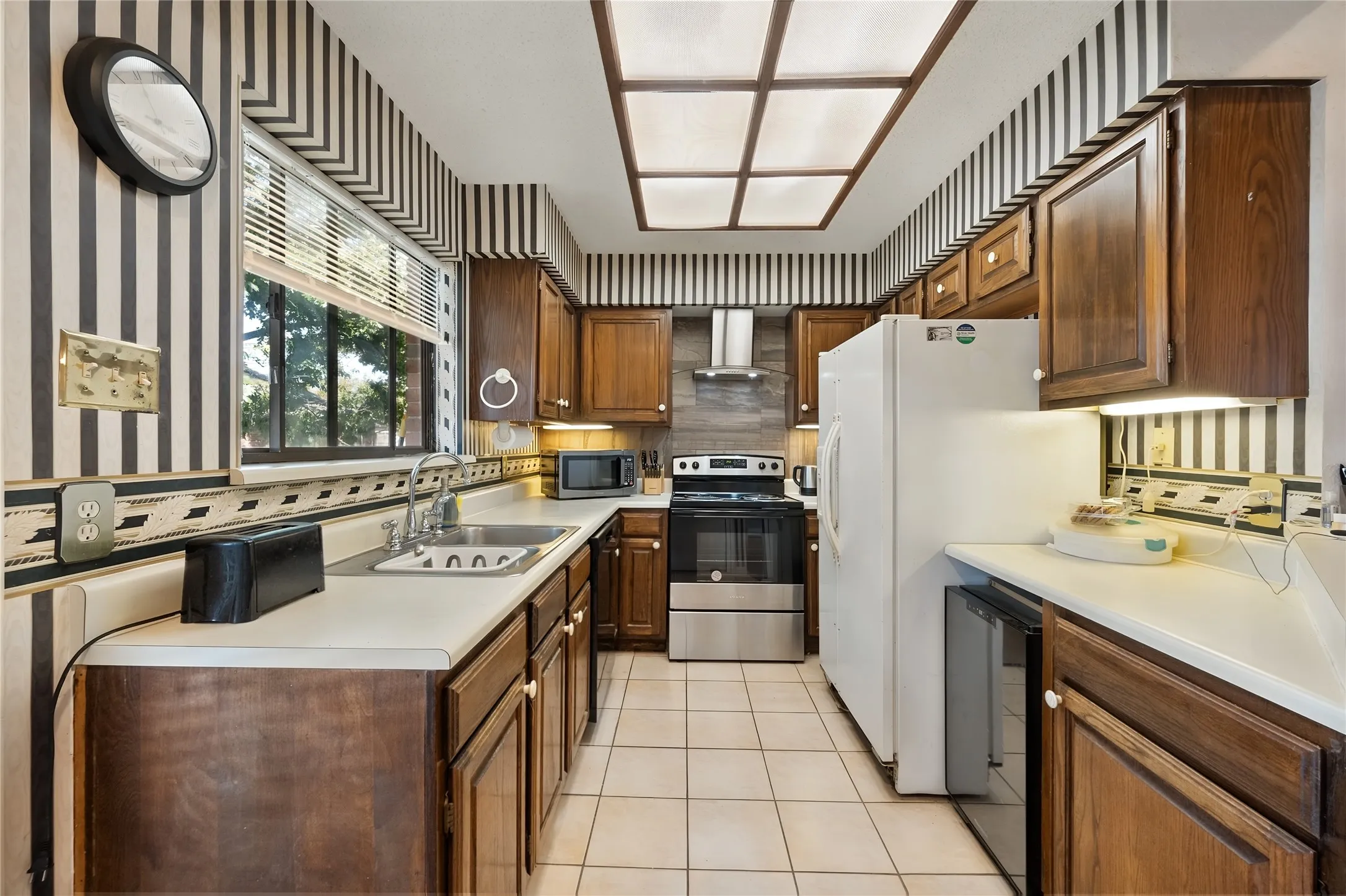Galley kitchen with new dishwasher, stove, venthood and backsplash