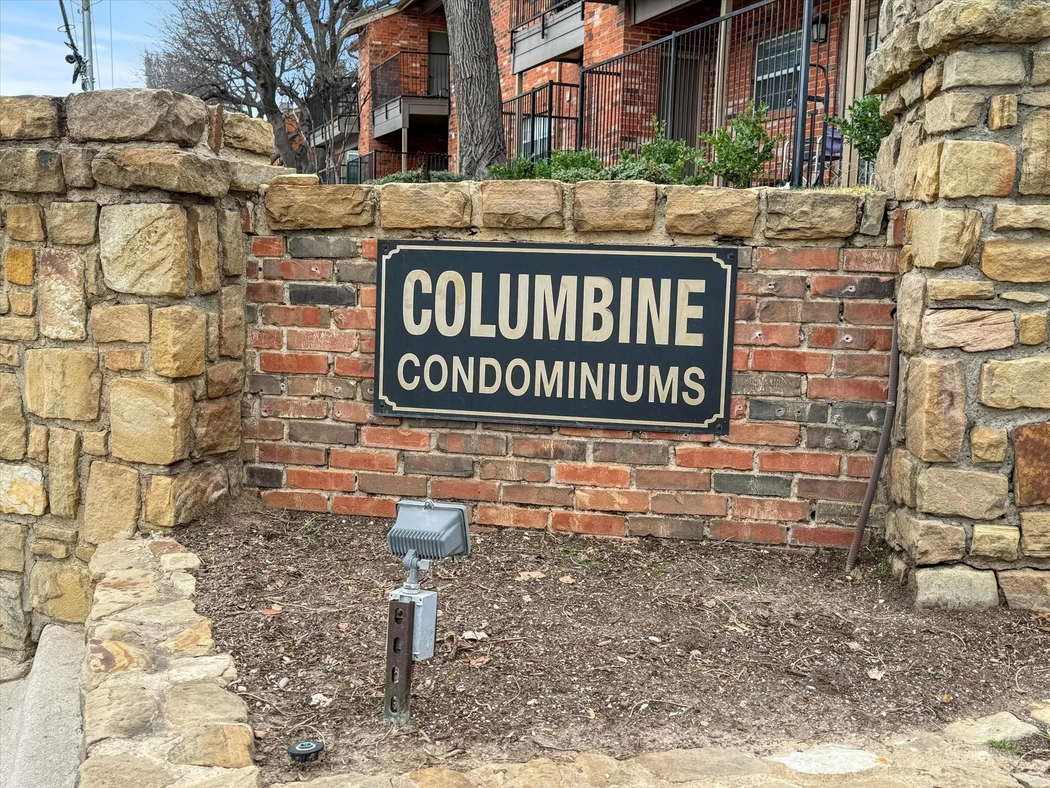 Stone and brick entrance signage featuring integrated outdoor lighting