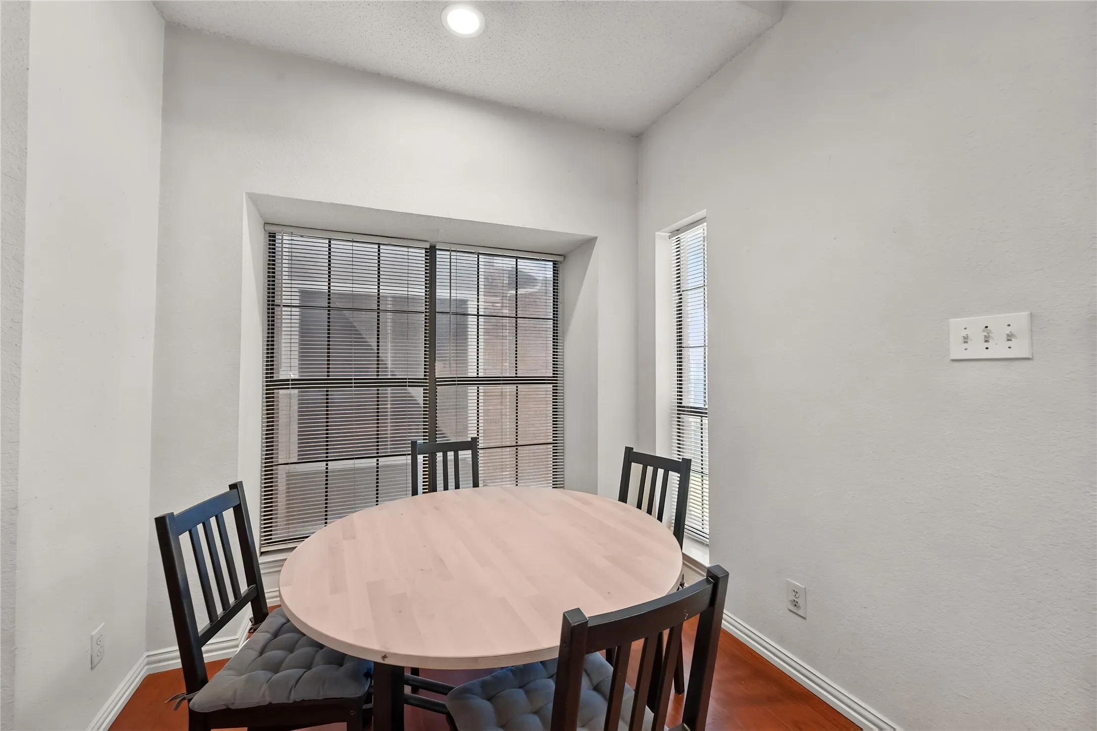 Recessed ceiling lighting, wood-finish flooring, and multiple windows with blinds